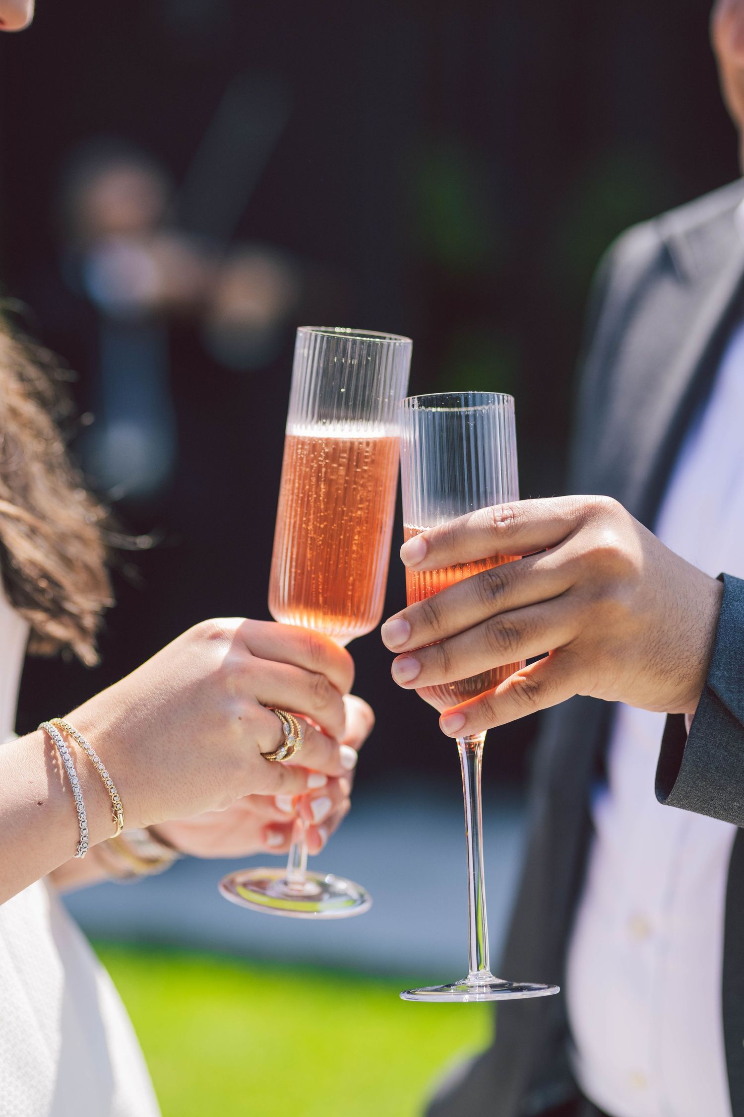 Hands holding champagne flutes for a celebratory toast against a dark background.
