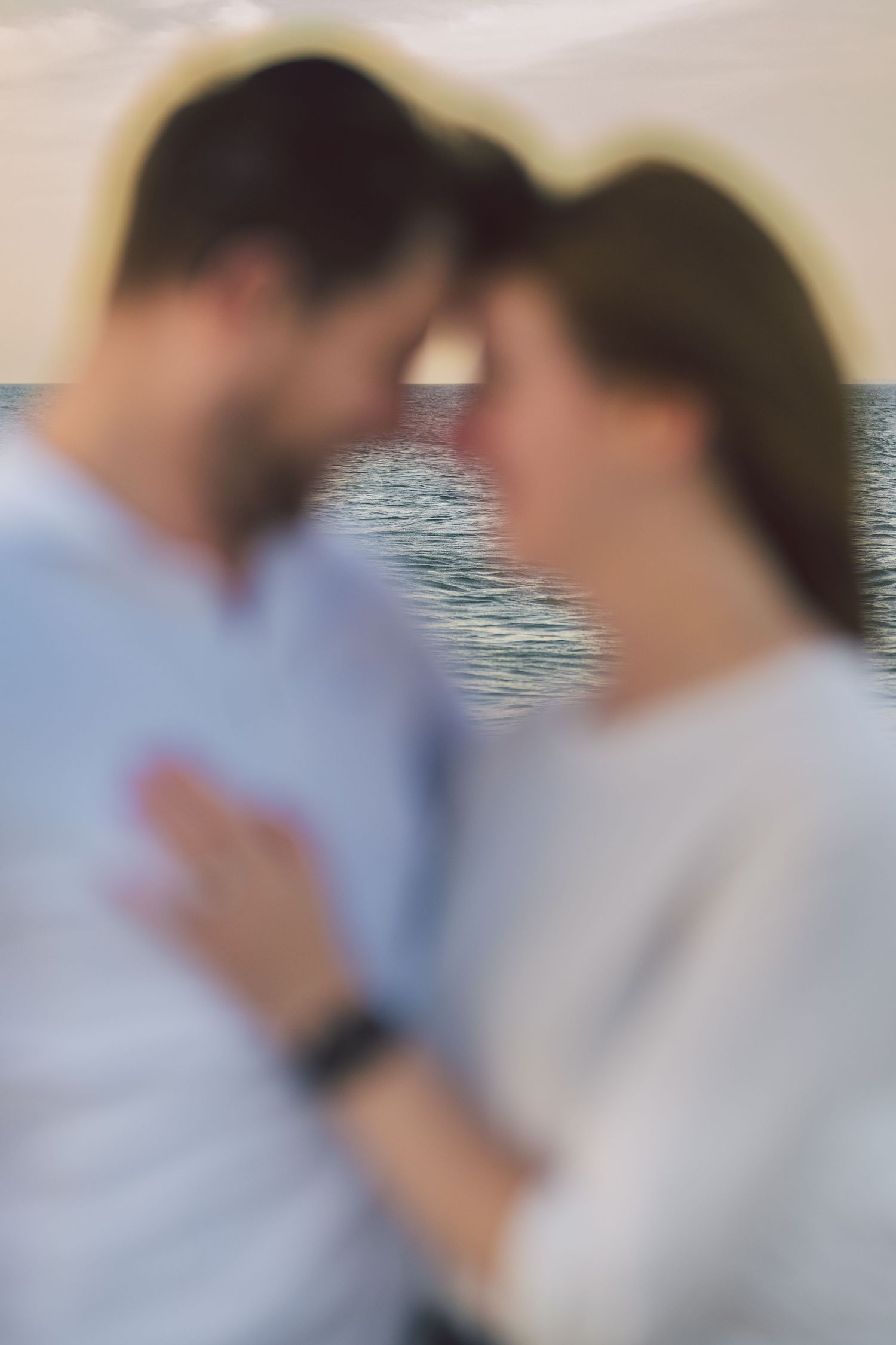 Romantic couple sharing an intimate moment together by the ocean at sunset.