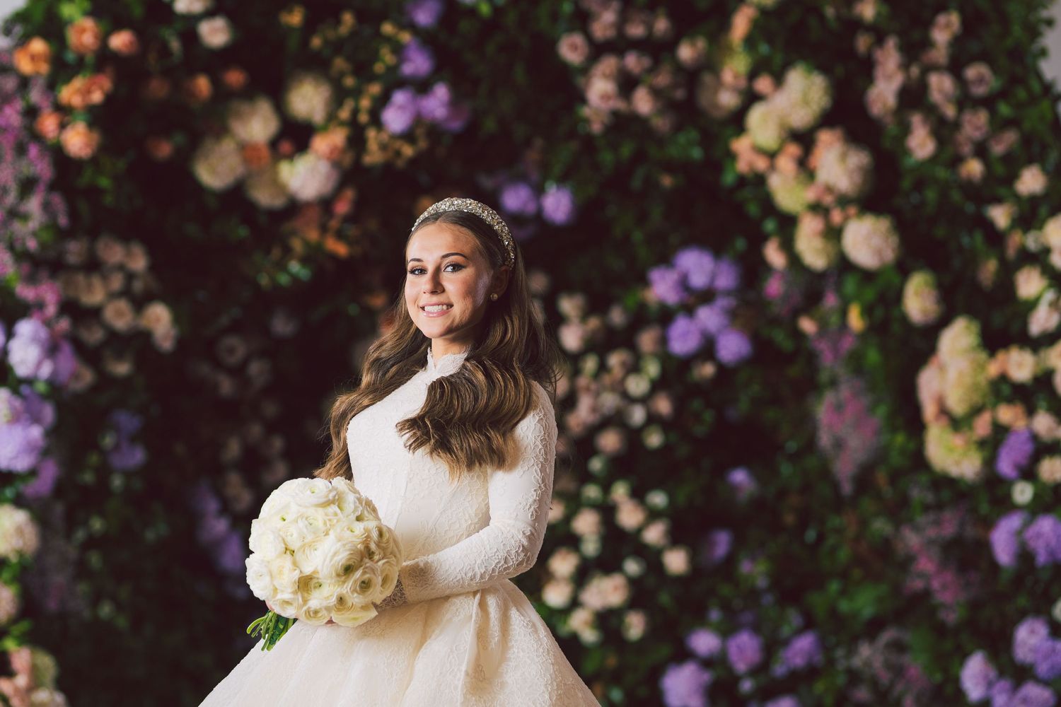Wedding portrait with lush floral backdrop featuring purple and peach blooms.