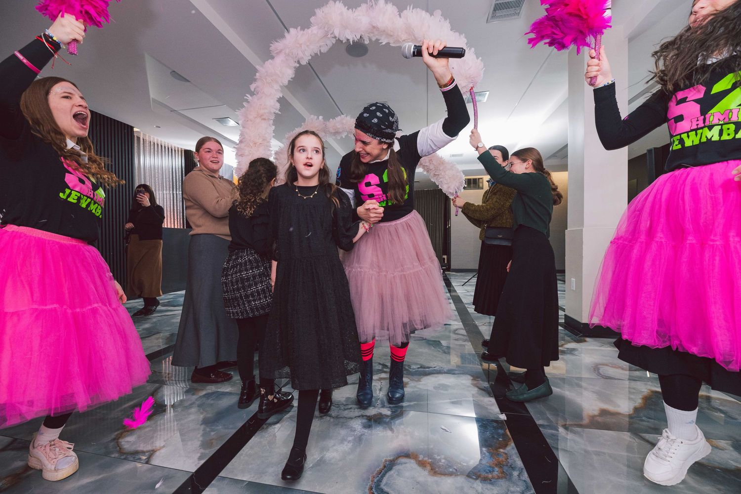 People dancing and celebrating in a room decorated with pink tulle and festive lighting.