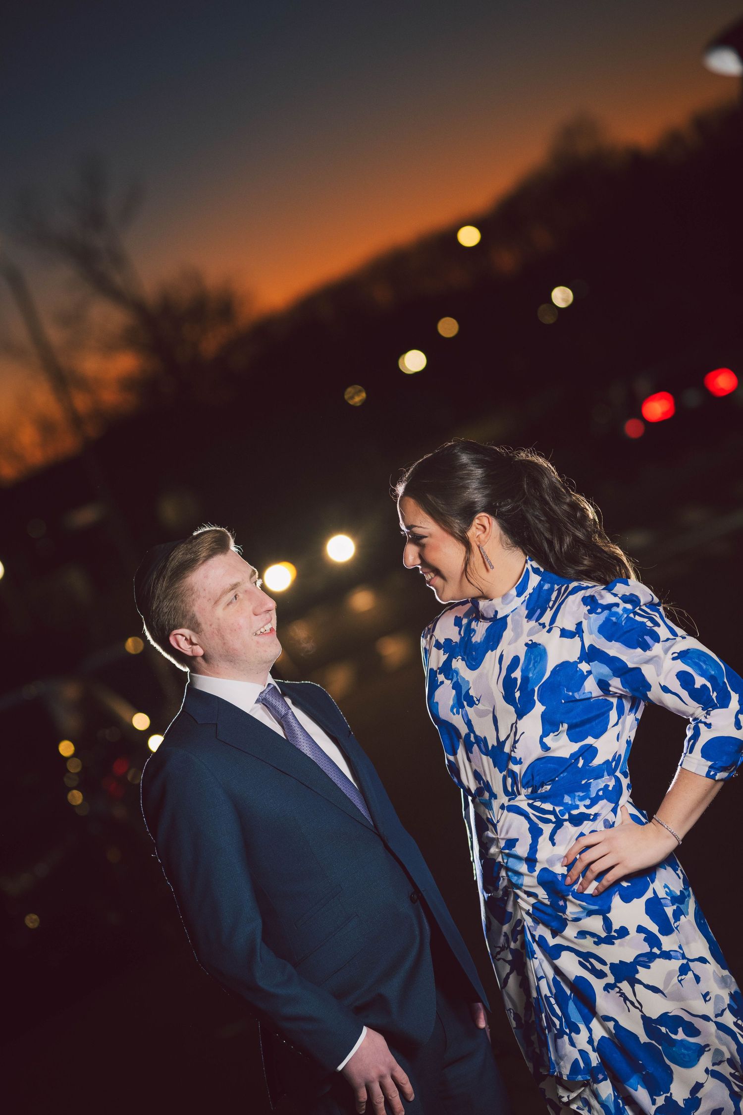 A romantic nighttime photoshoot with soft lighting and glowing bokeh in the background.