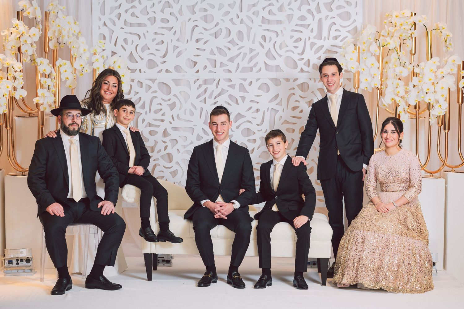 Formal group photo with elegant attire against decorative white and gold backdrop.