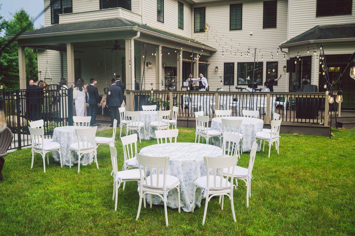 Outdoor wedding venue with white chairs set up on lawn in front of historic white house.