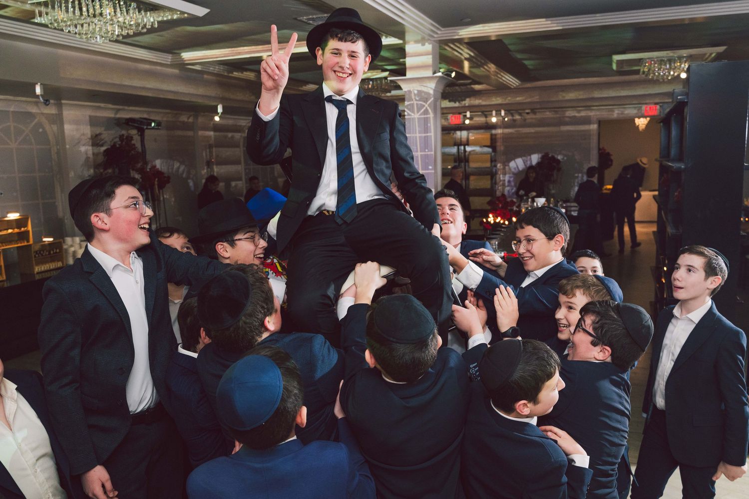 Celebratory scene with crowd lifting person during formal event.