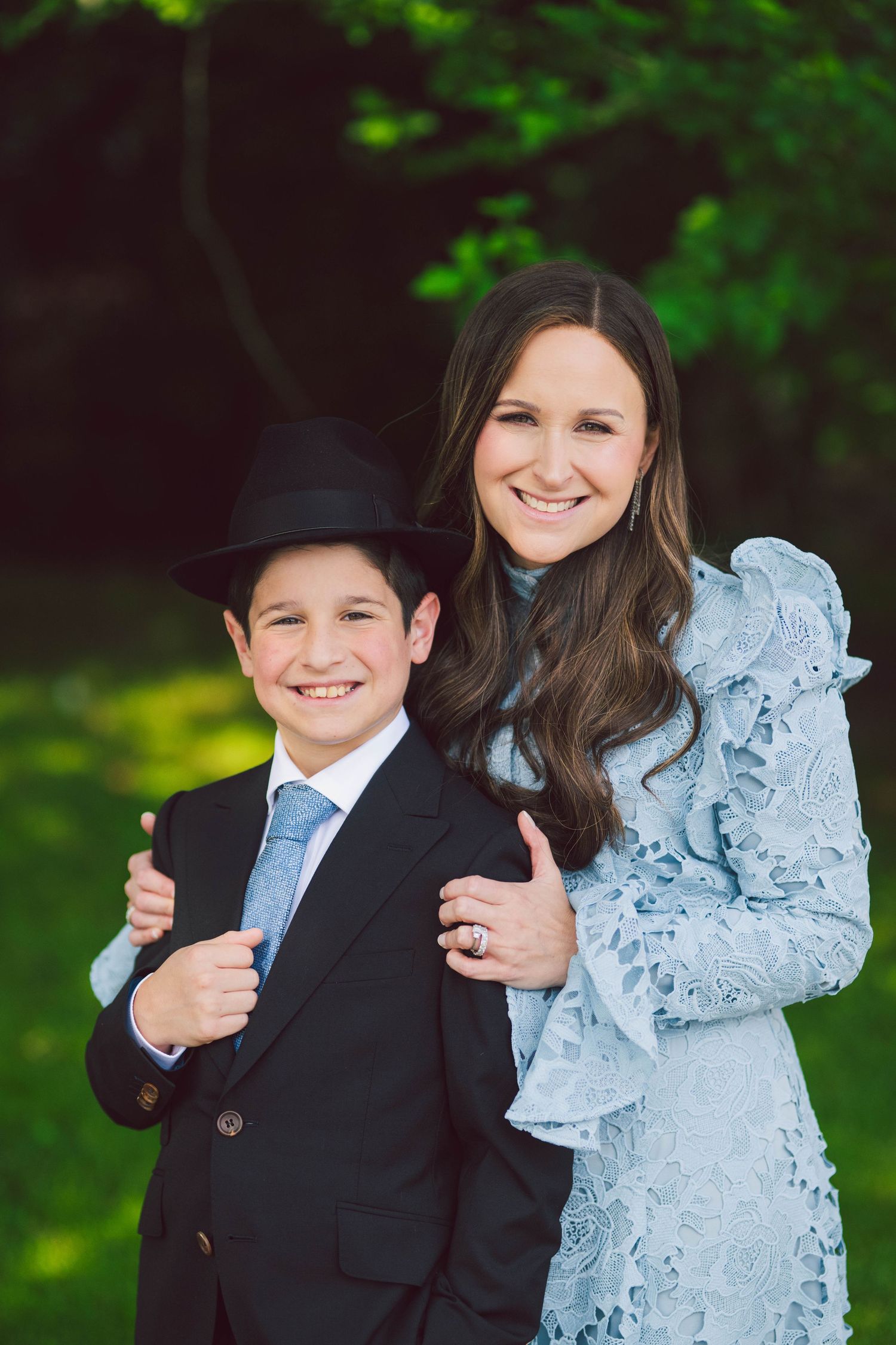 Children dressed in formal wear posing playfully for portraits in a garden setting.