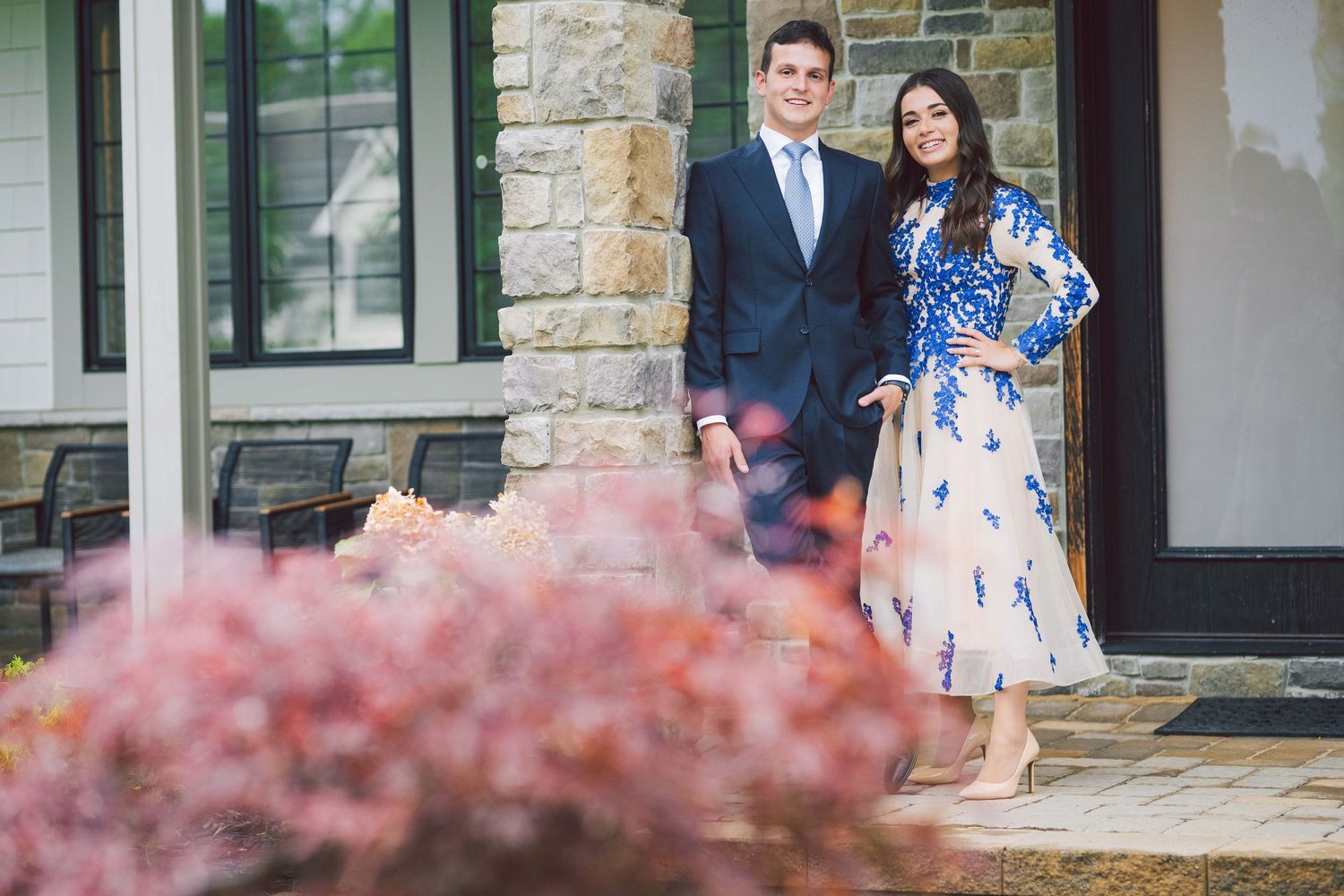 Spring wedding scene with pink flowering bushes in foreground of stone building.