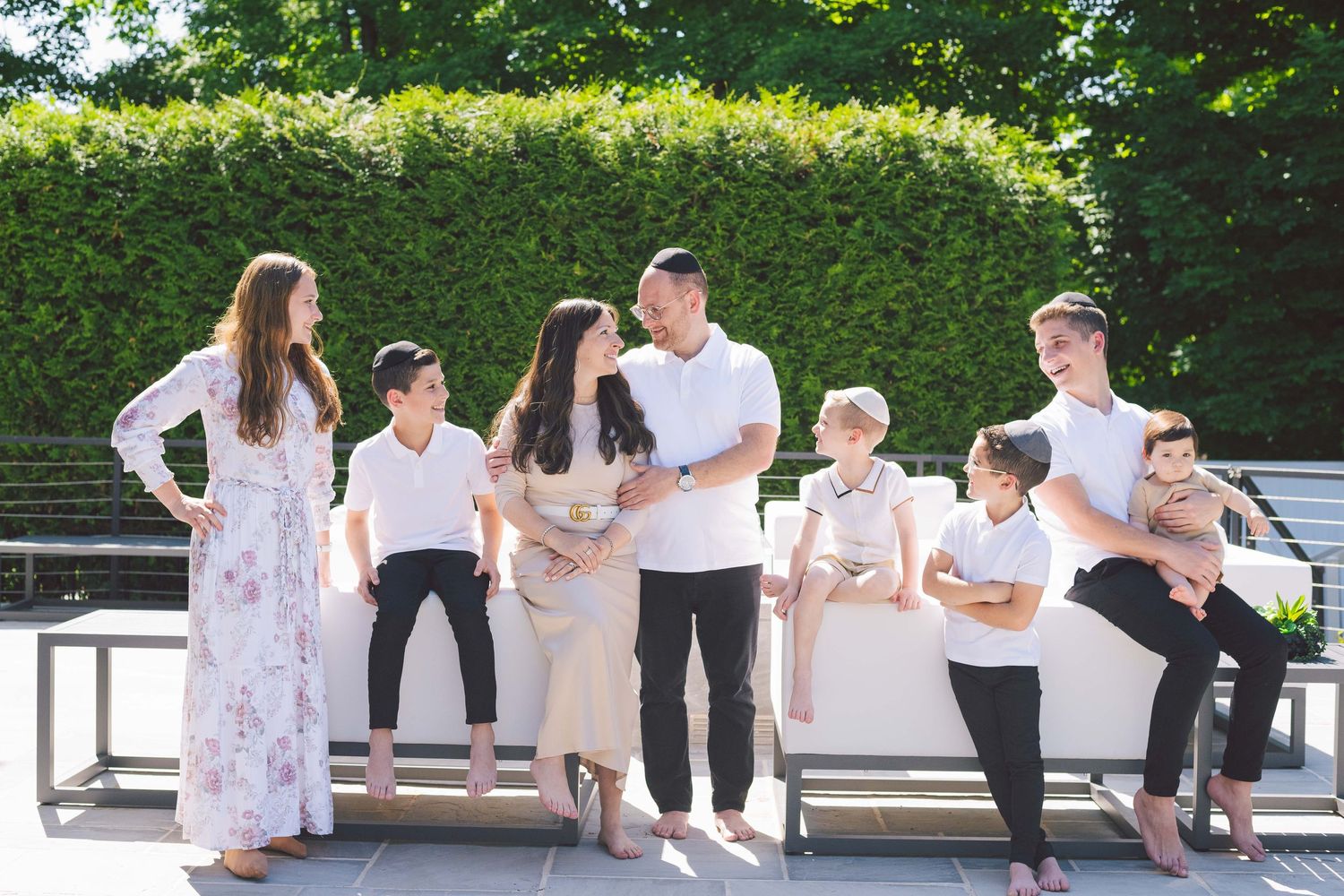 Candid family portraits on white benches showing playful moments outdoors.