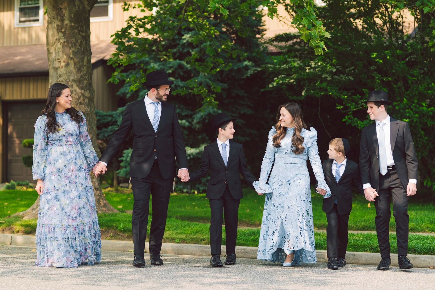 Group photo session in formal attire taken outdoors with lush green background.