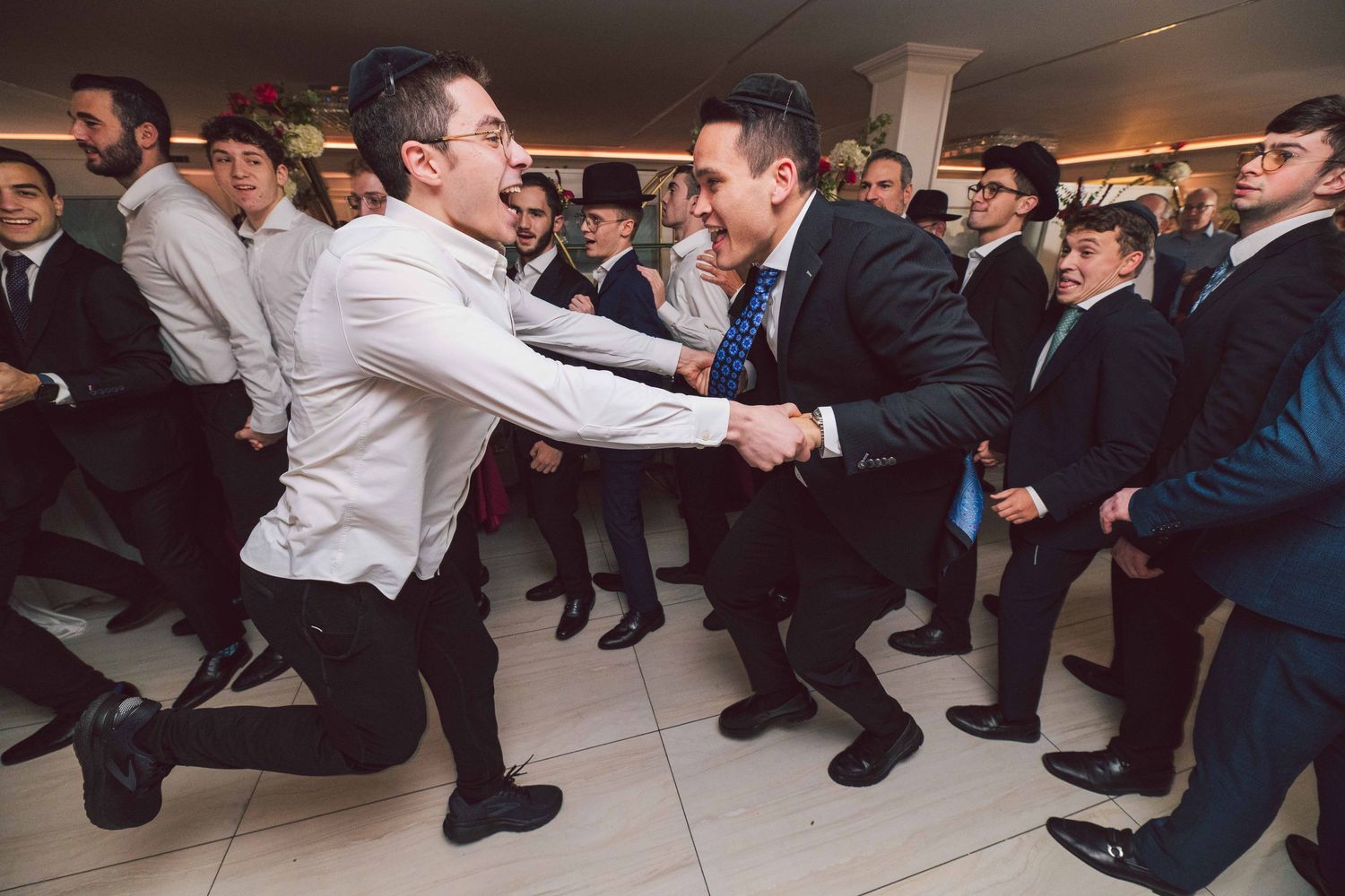 Wedding party members kneeling in formal attire during celebration.
