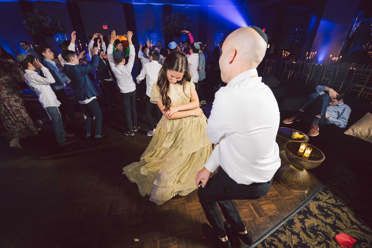 People dancing and celebrating at a nightclub with blue lighting and energetic atmosphere.