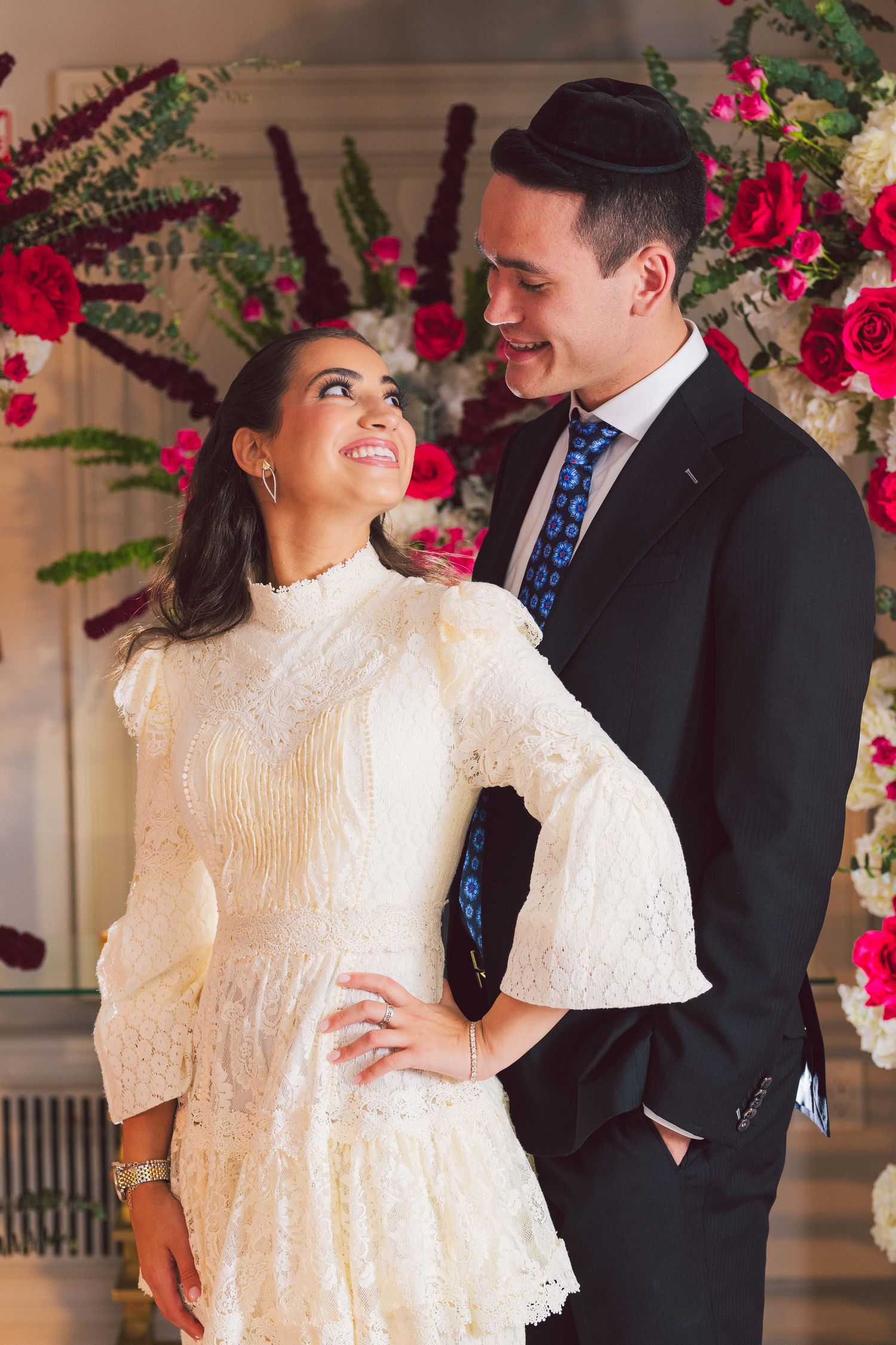 Wedding celebration with elegant white lace dress and red rose decorations.