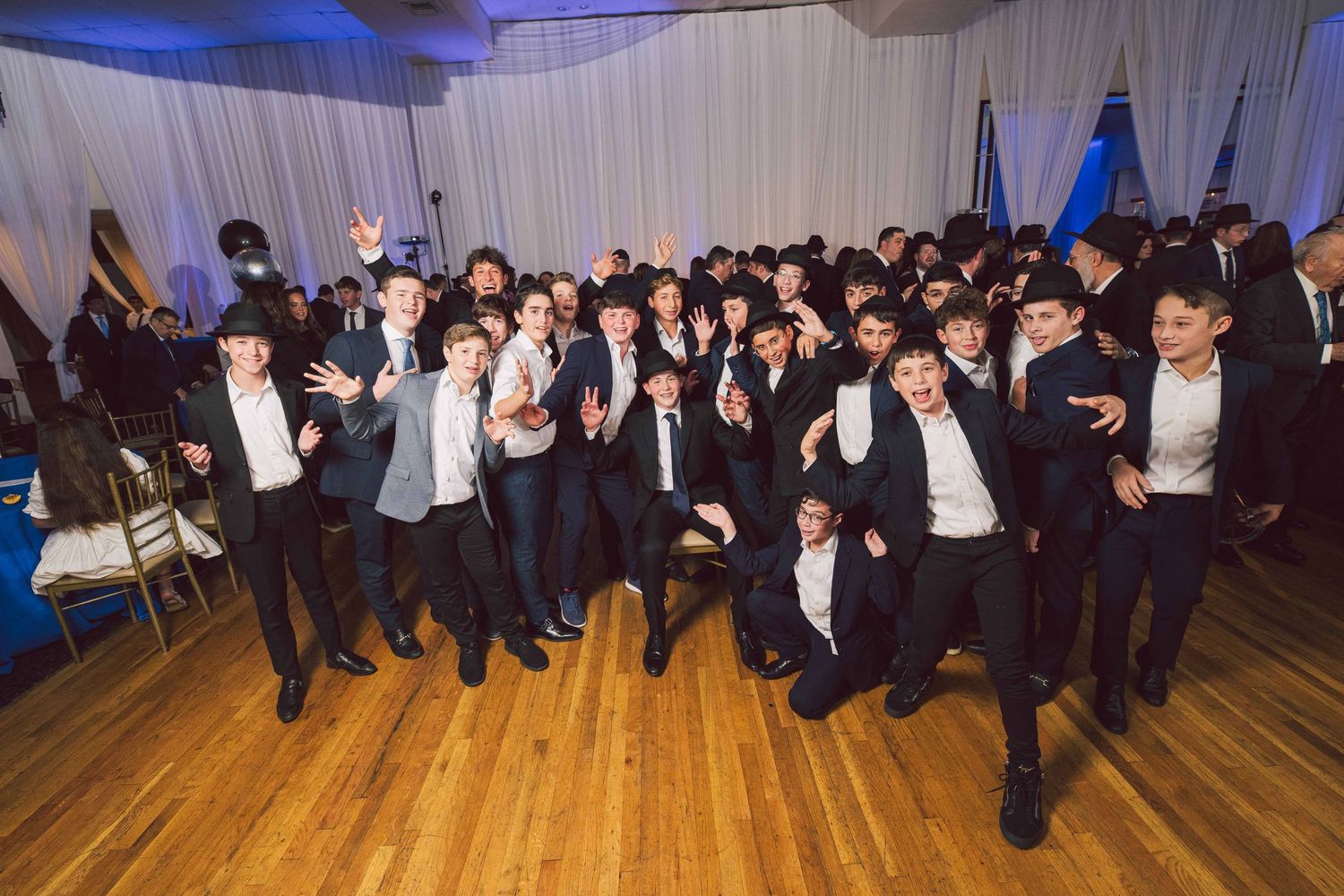 Large group of formally dressed guests celebrating at an indoor event.
