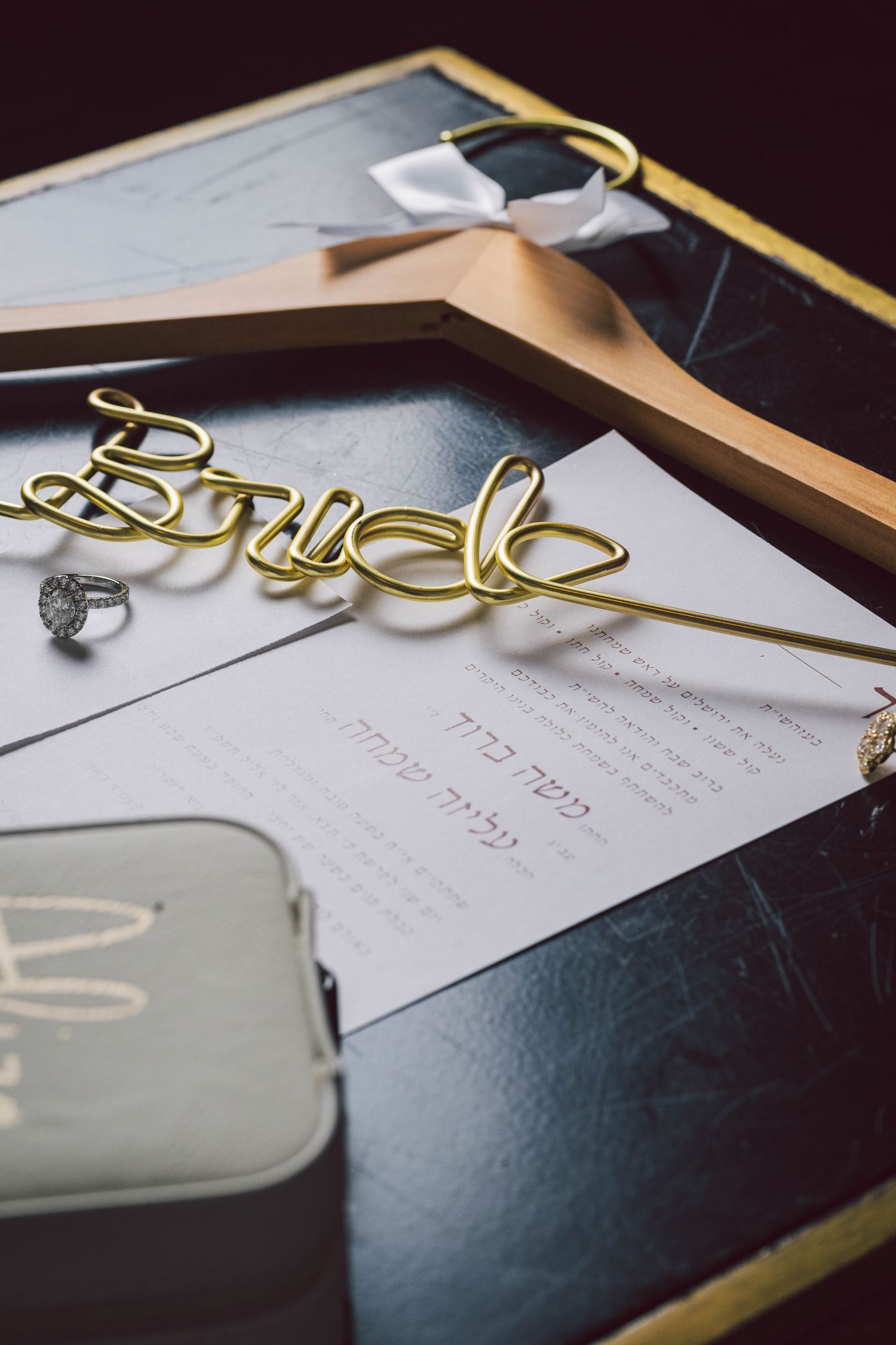 Wedding invitation and decorative gold details laid out on dark surface.