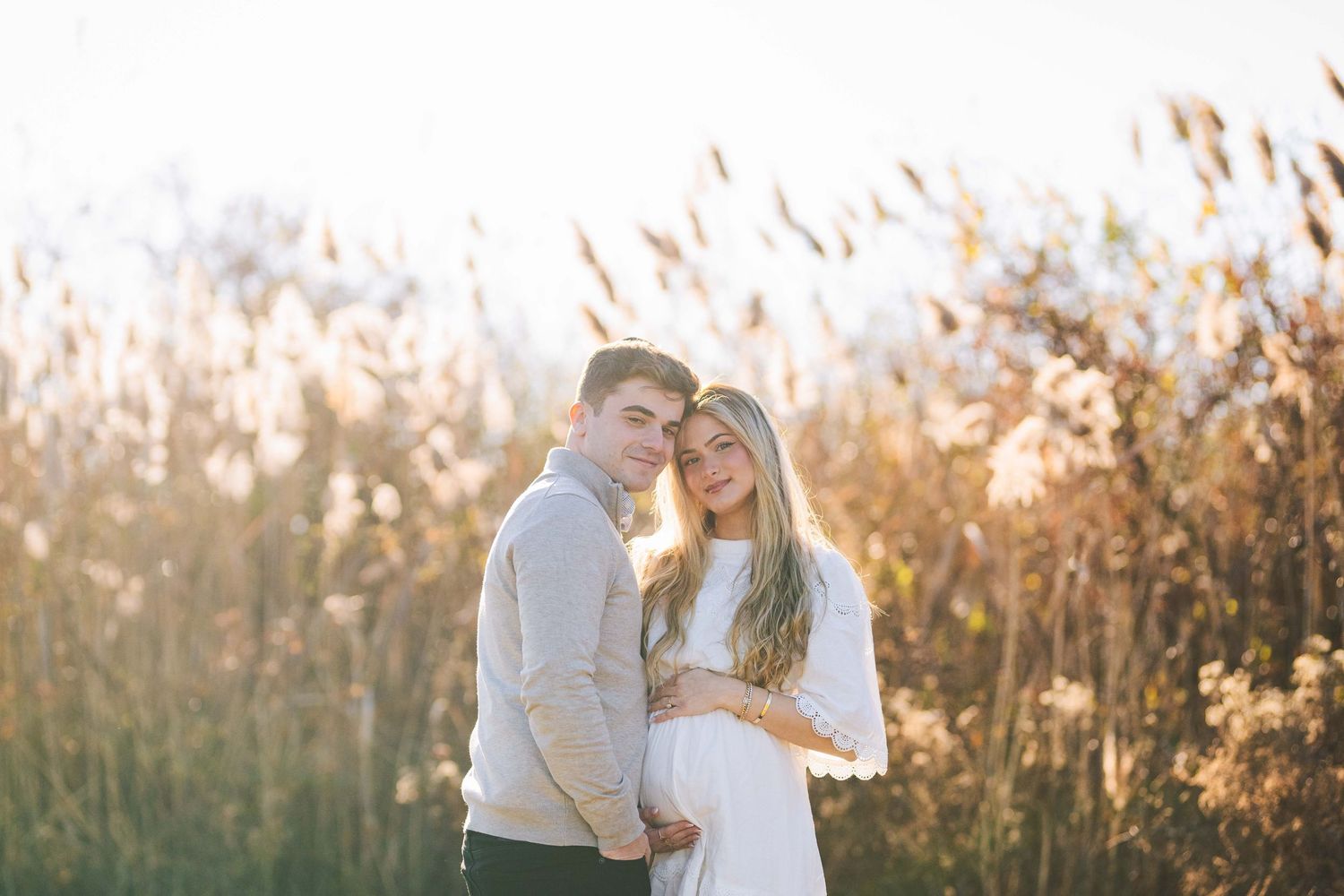 A romantic sunset photoshoot in a field showing intimate moments between a couple.