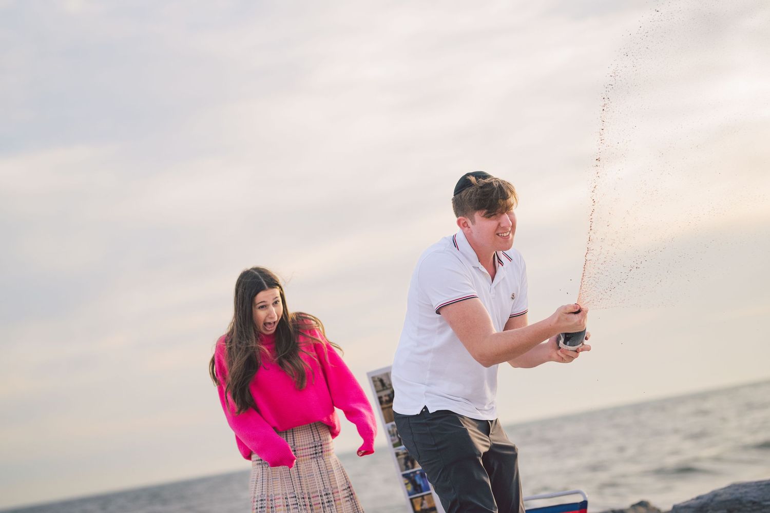 Couple enjoys romantic beach picnic at sunset with proposal setup.