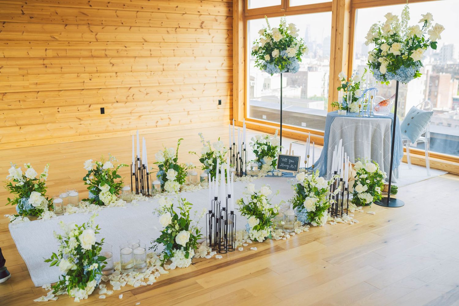 Modern wooden interior space with large windows and decorative greenery arrangements.