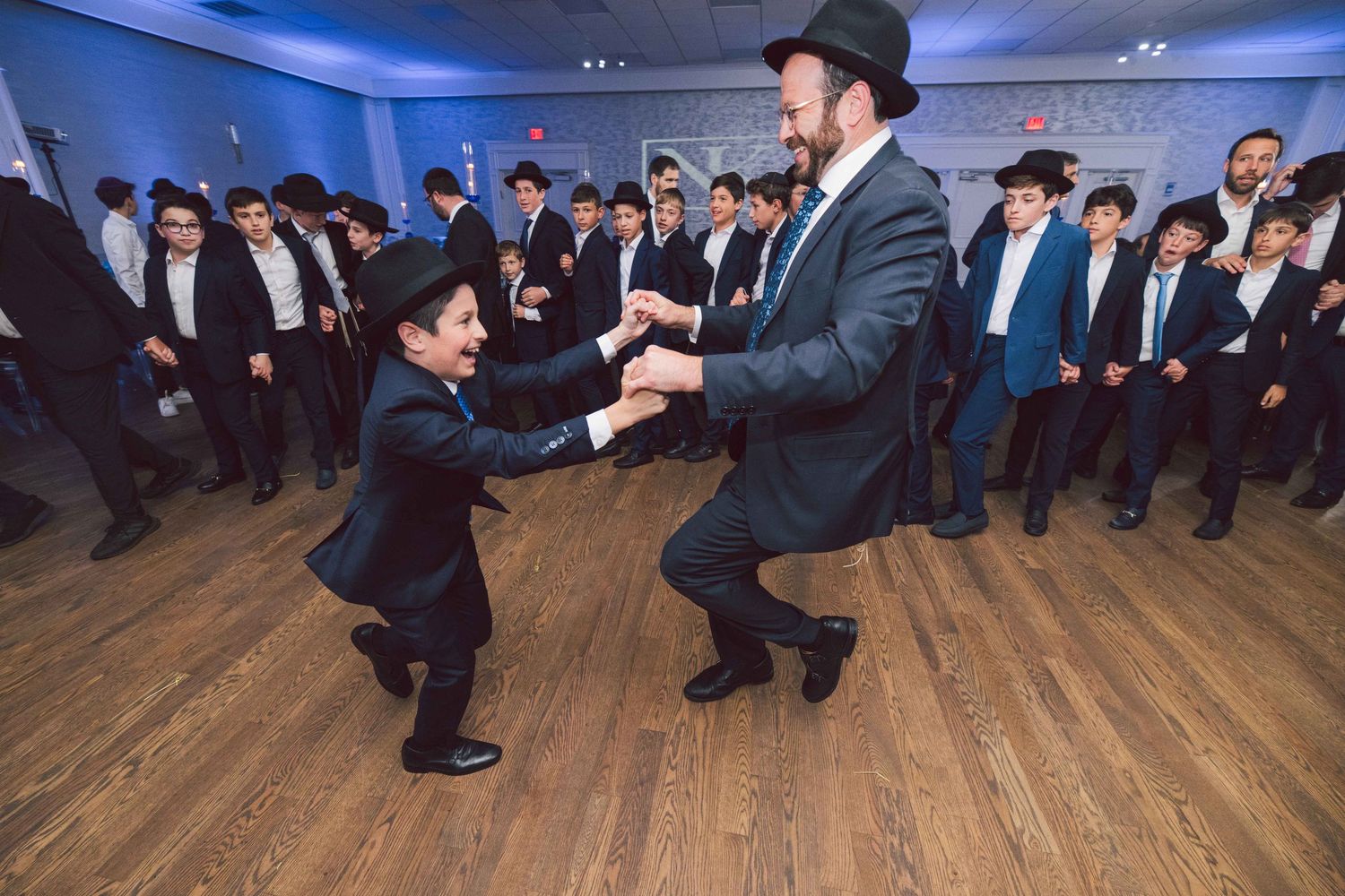 A sequence of traditional Jewish wedding dance moves performed on a wooden dance floor at a celebration.