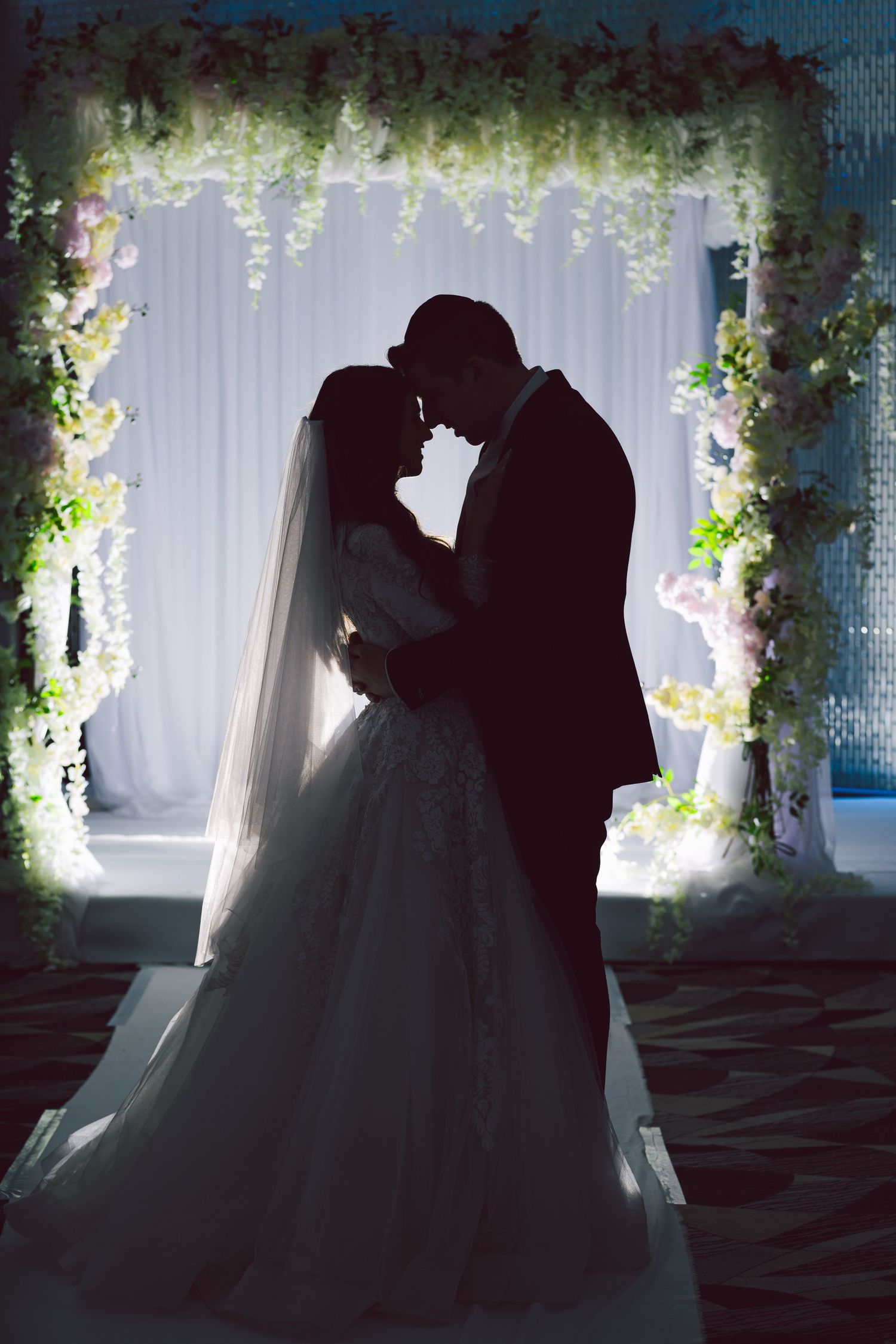 Romantic silhouettes of a couple in a decorative indoor setting with floral archways.