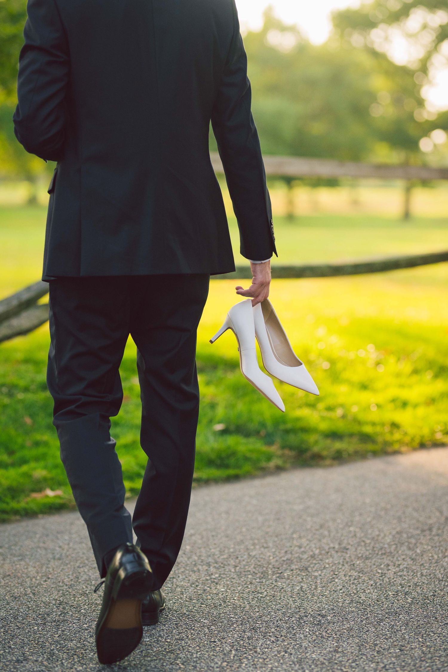 Person in formal suit walking on path holding white handkerchief.