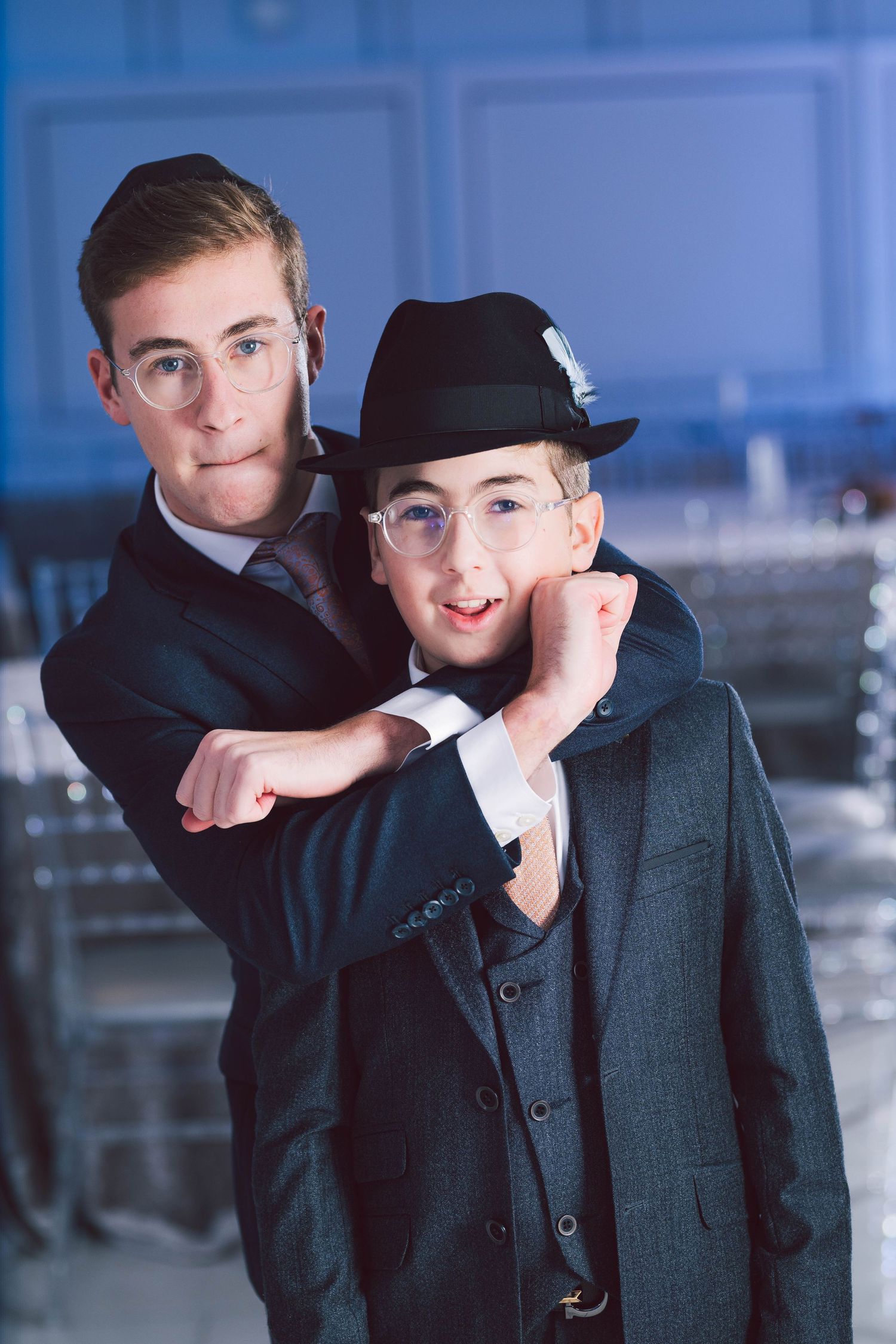 A series of four photos showing two people in formal attire posing playfully in a modern indoor setting.