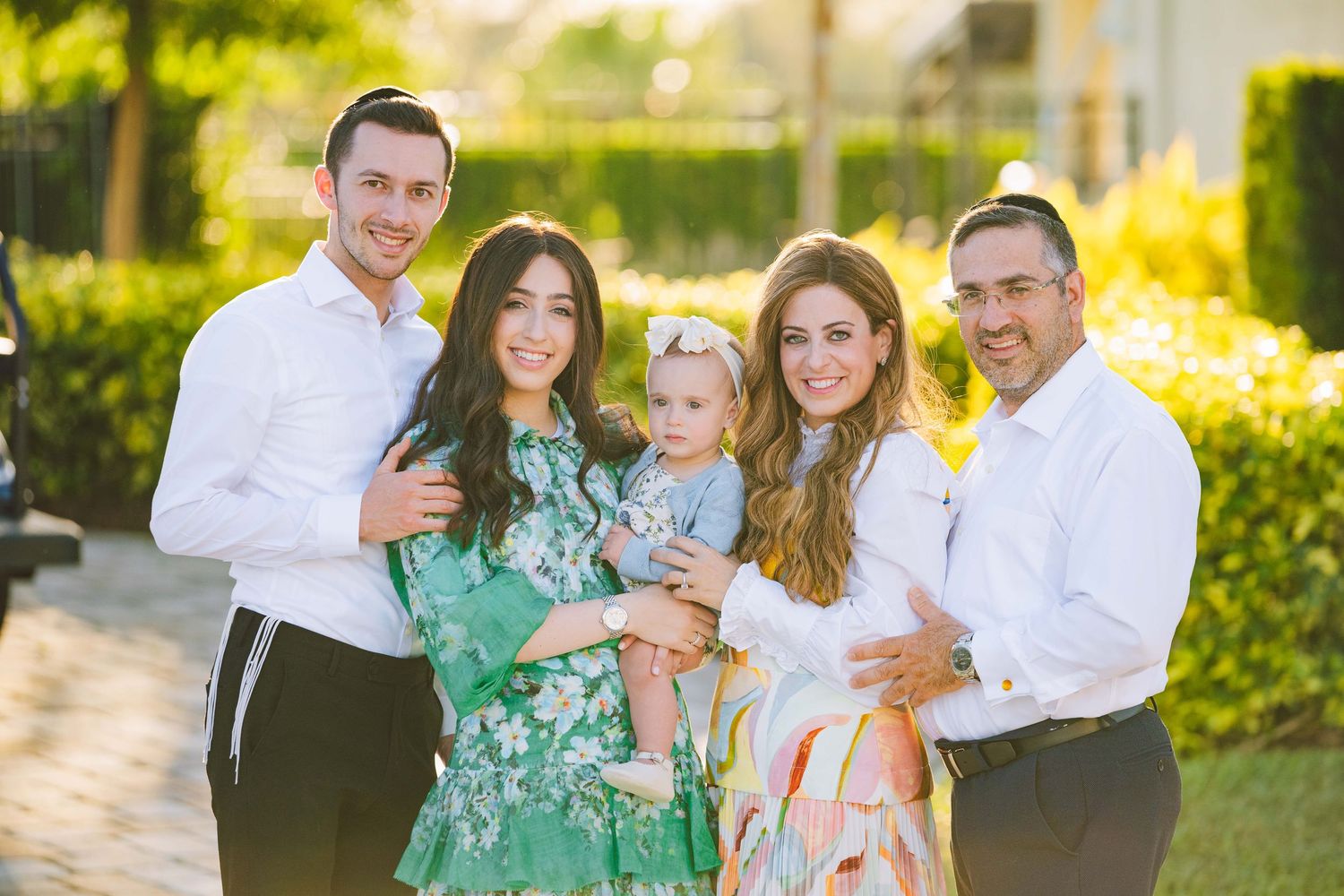 Family portrait session taking place outdoors with palm trees and sunlight creating a warm golden glow.