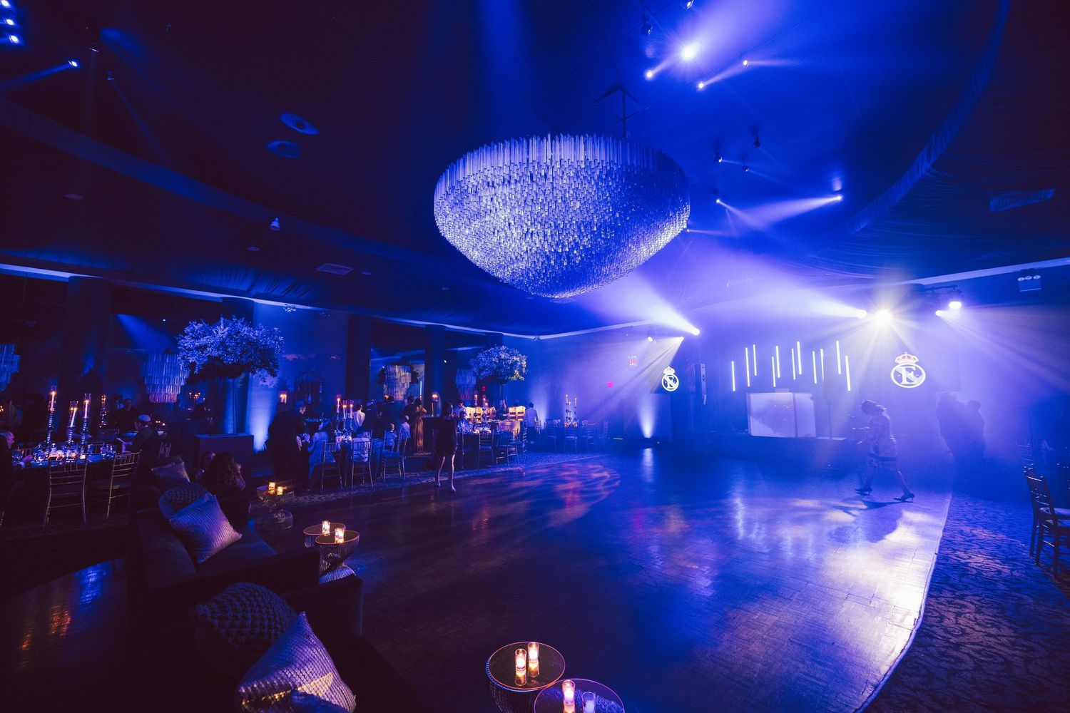 Luxurious ballroom with blue ambient lighting and crystal chandelier.