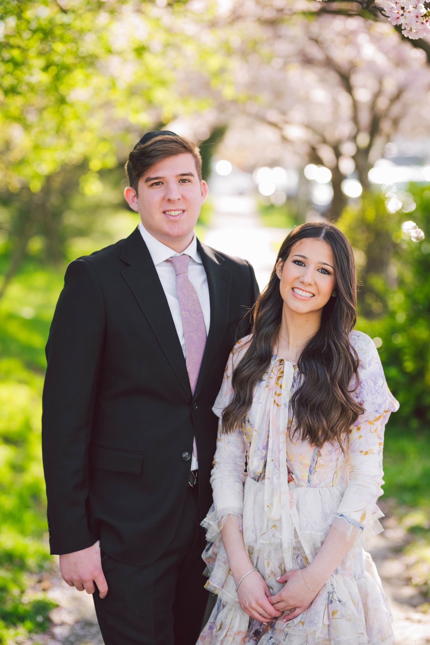 Spring engagement photo session with cherry blossoms and formal attire.