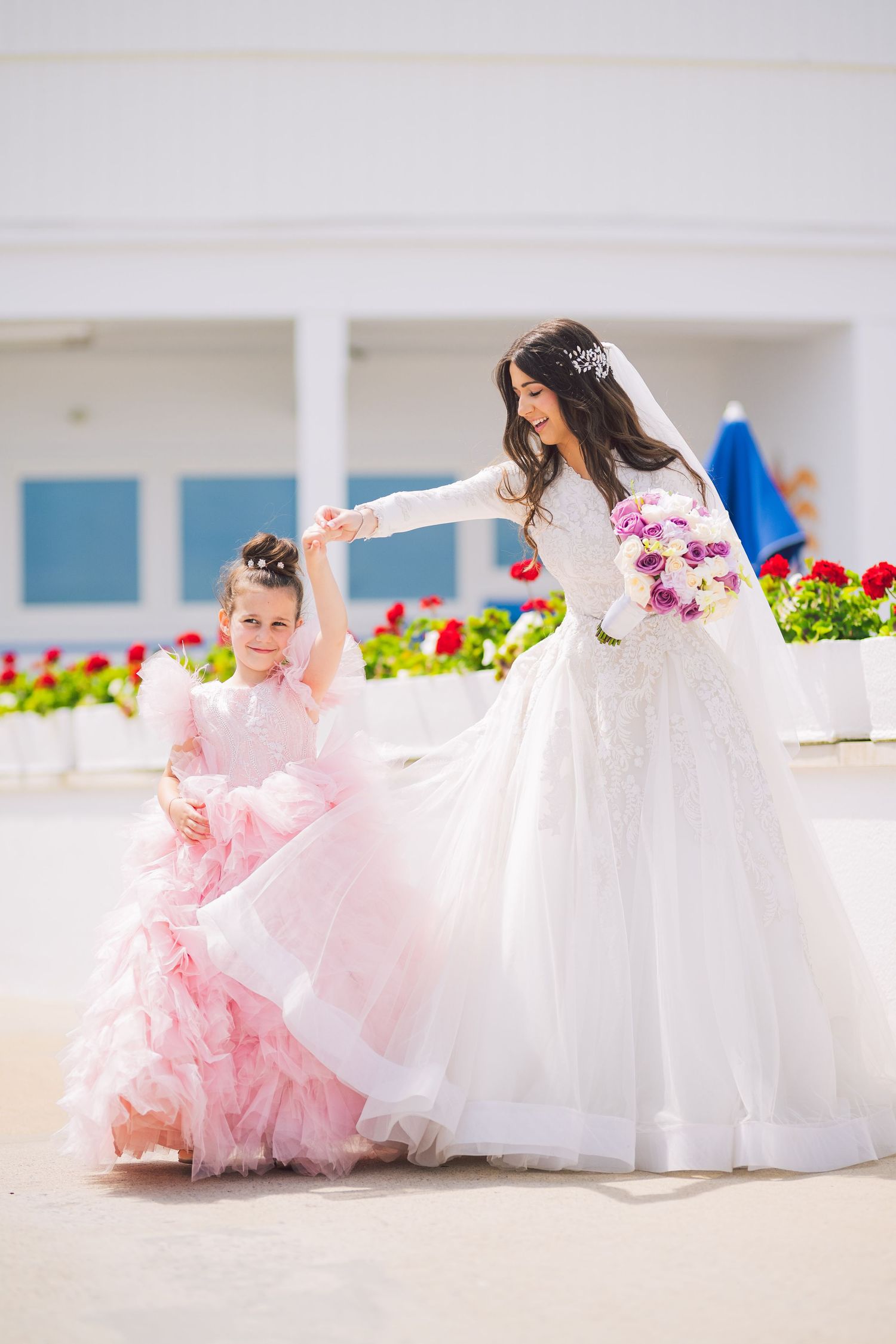 Wedding party in white and pink dresses poses on bright outdoor terrace.