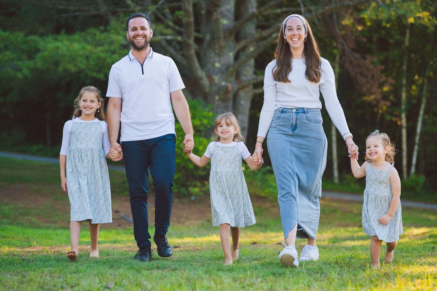Family walking together through a green park wearing coordinated blue and white outfits.