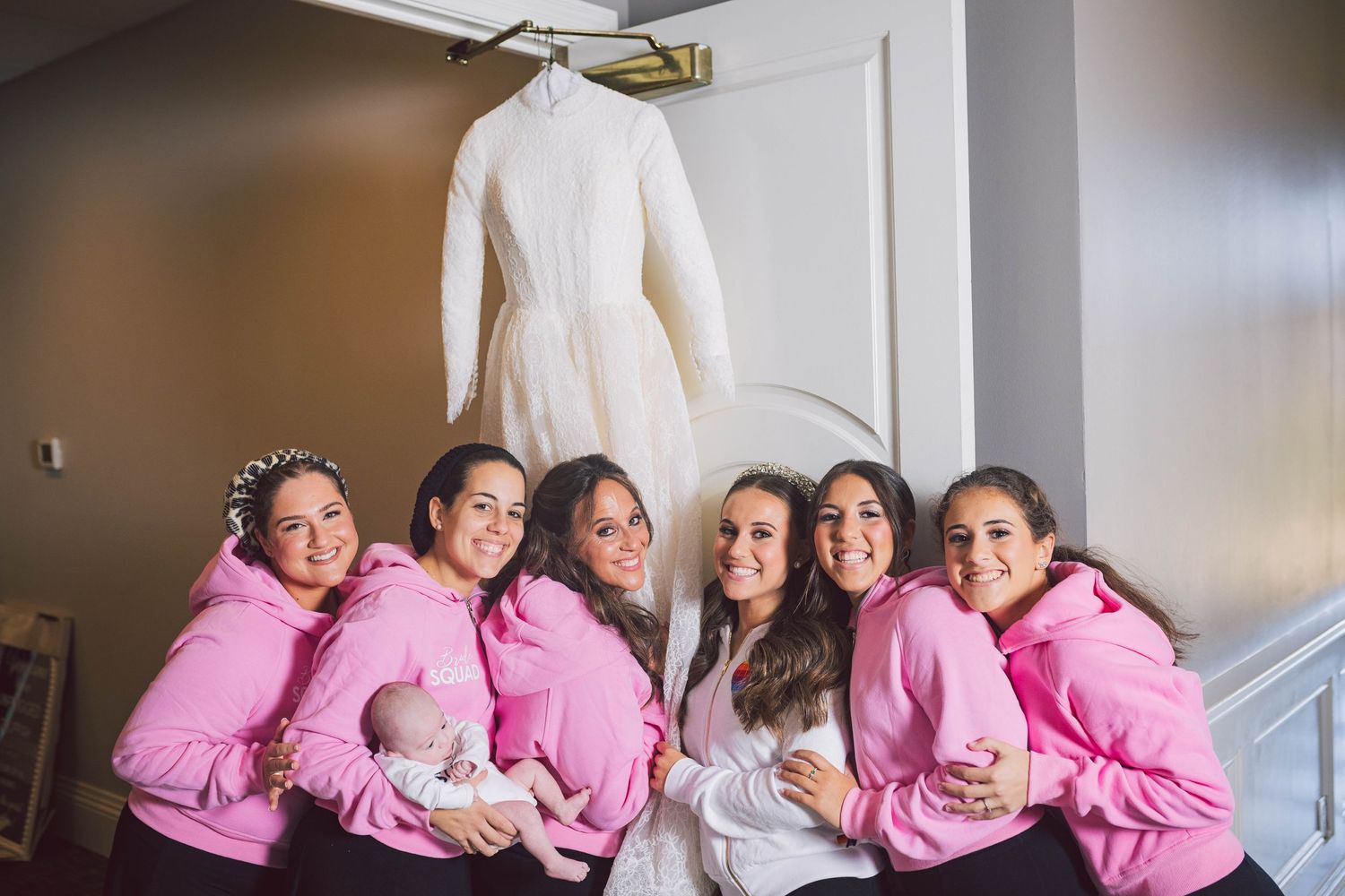 Wedding party wearing matching pink robes poses together indoors.