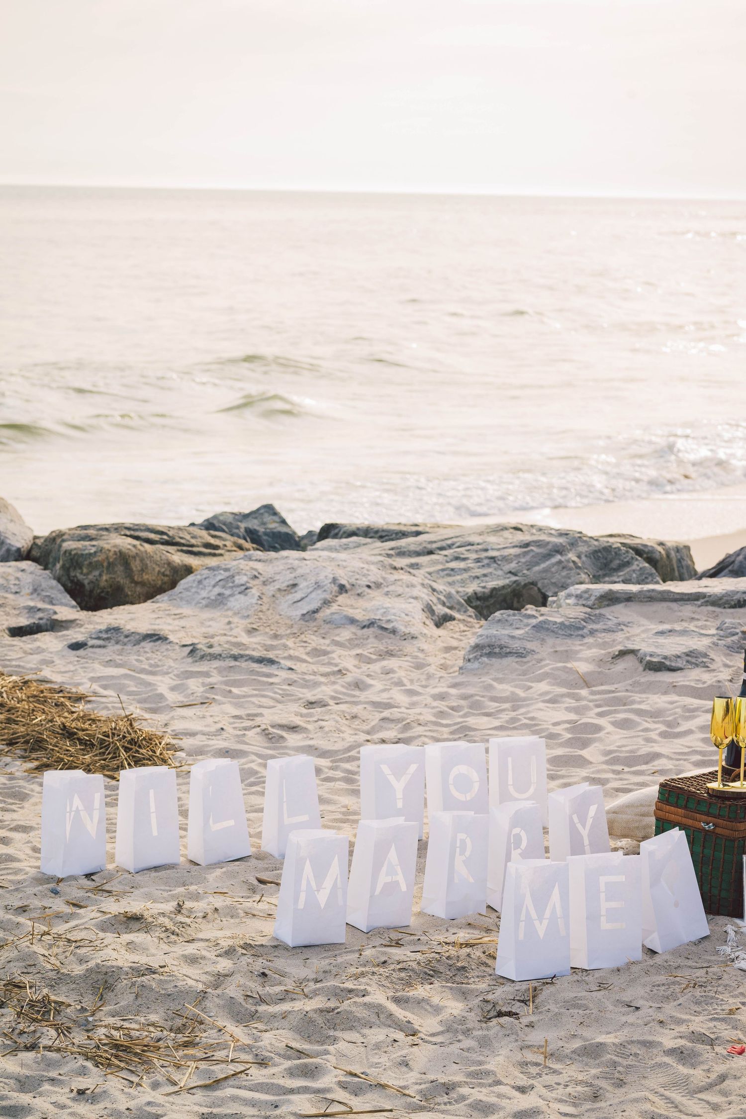 White letter decorations spelling out a message on sandy beach near ocean waves.