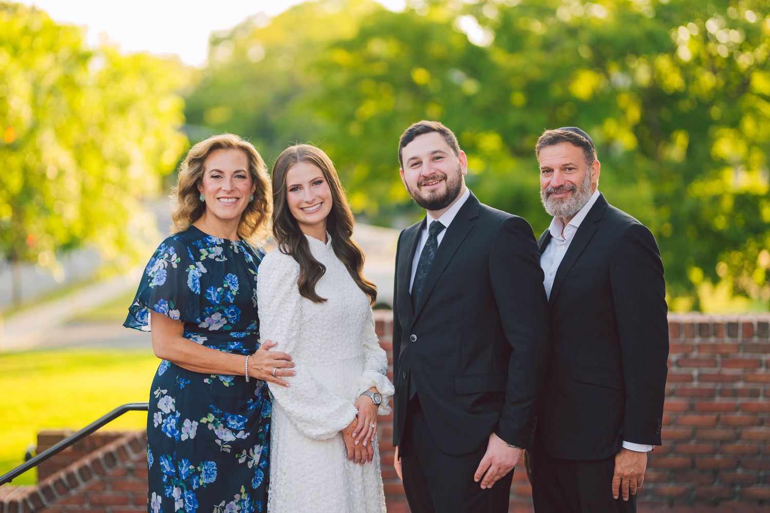 Outdoor family celebration photos with group gathered in garden setting at sunset.