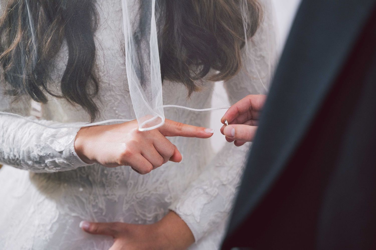 A close-up of hands exchanging a wedding ring during a wedding ceremony.