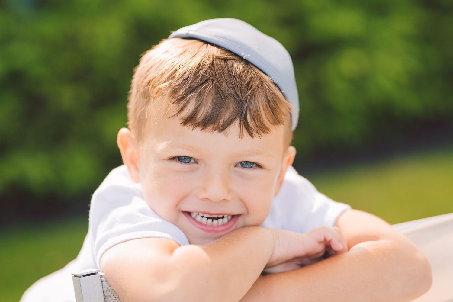 Child smiling brightly outdoors on a sunny day.