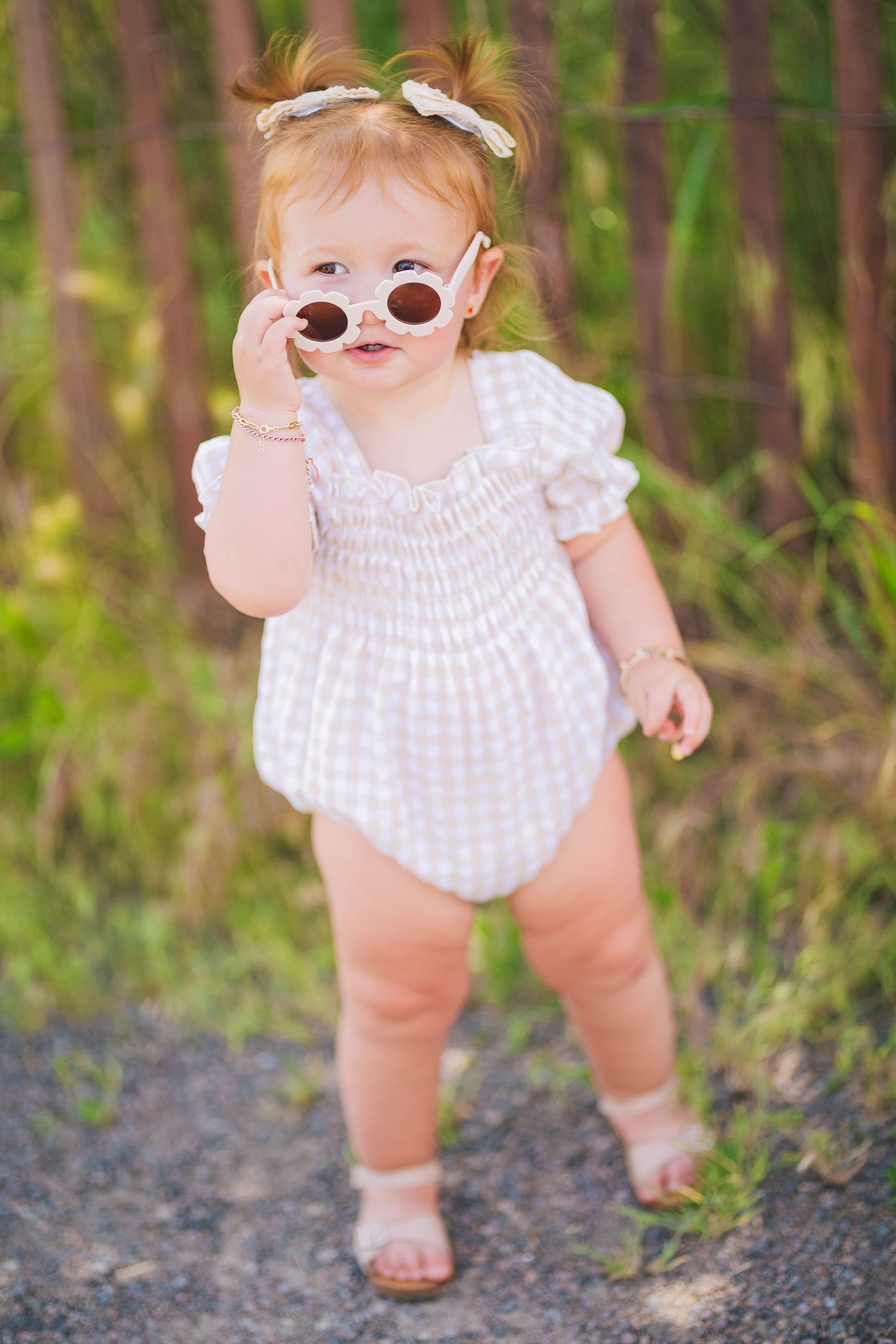 A toddler in a gingham smocked dress captured in a series of candid outdoor shots.