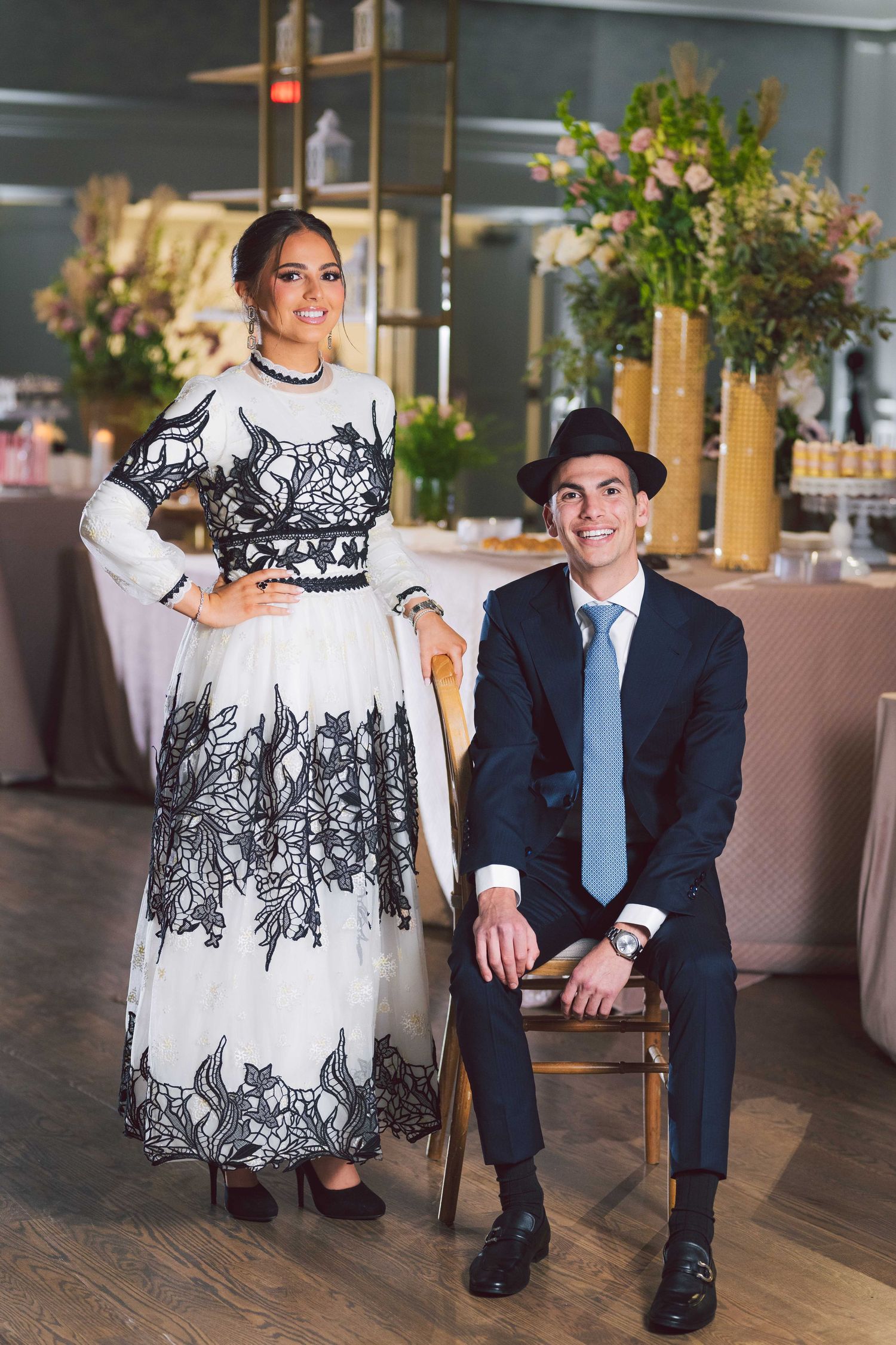 Couple in contrasting black and white formal attire seated in modern restaurant setting.