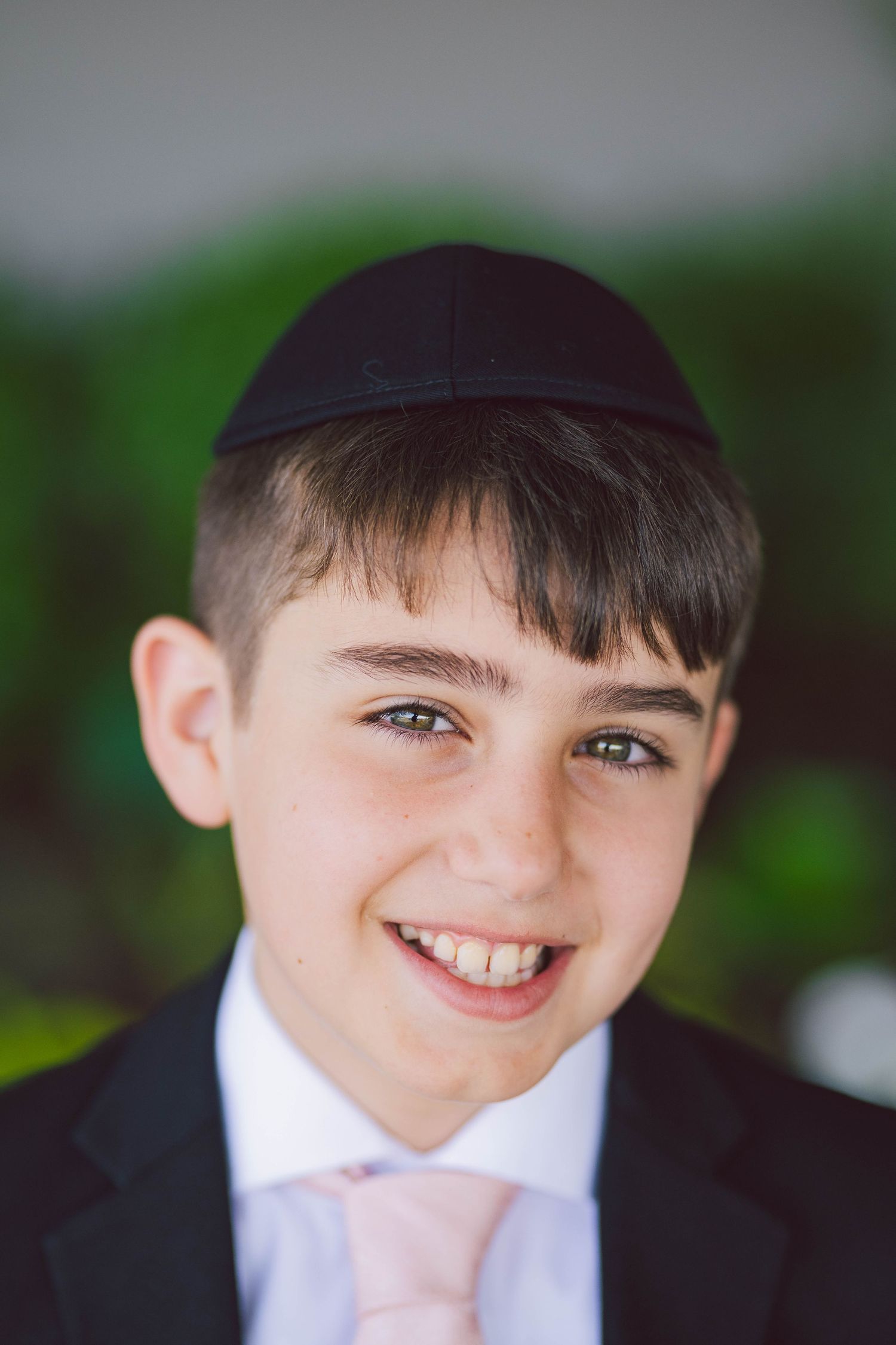 A young attendant in a black suit and pink tie smiling at the camera.