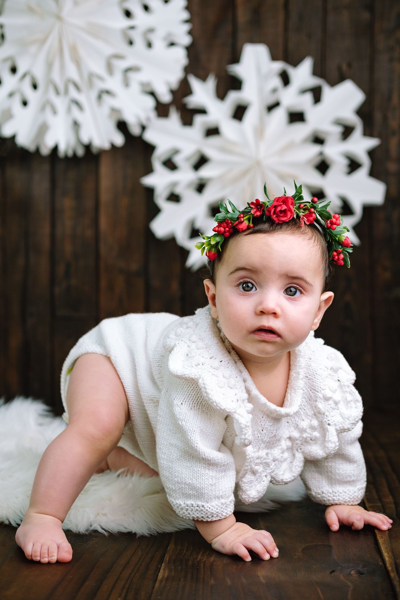 Nine-month-old baby in studio wearing a romper with a Christmas-themed setup