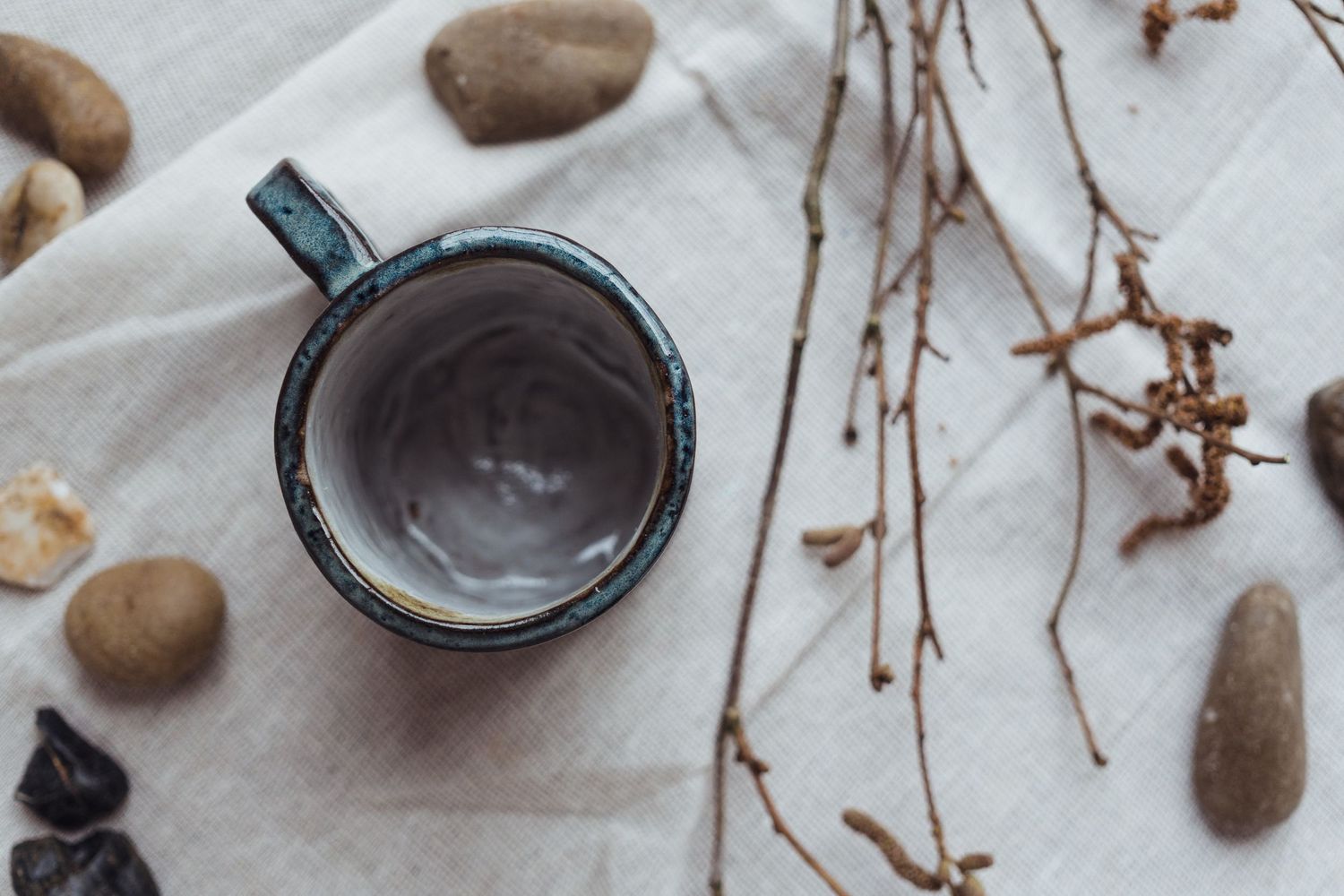 Rustic coffee brewing setup with scattered coffee beans and vintage coffee accessories on light marble surface.