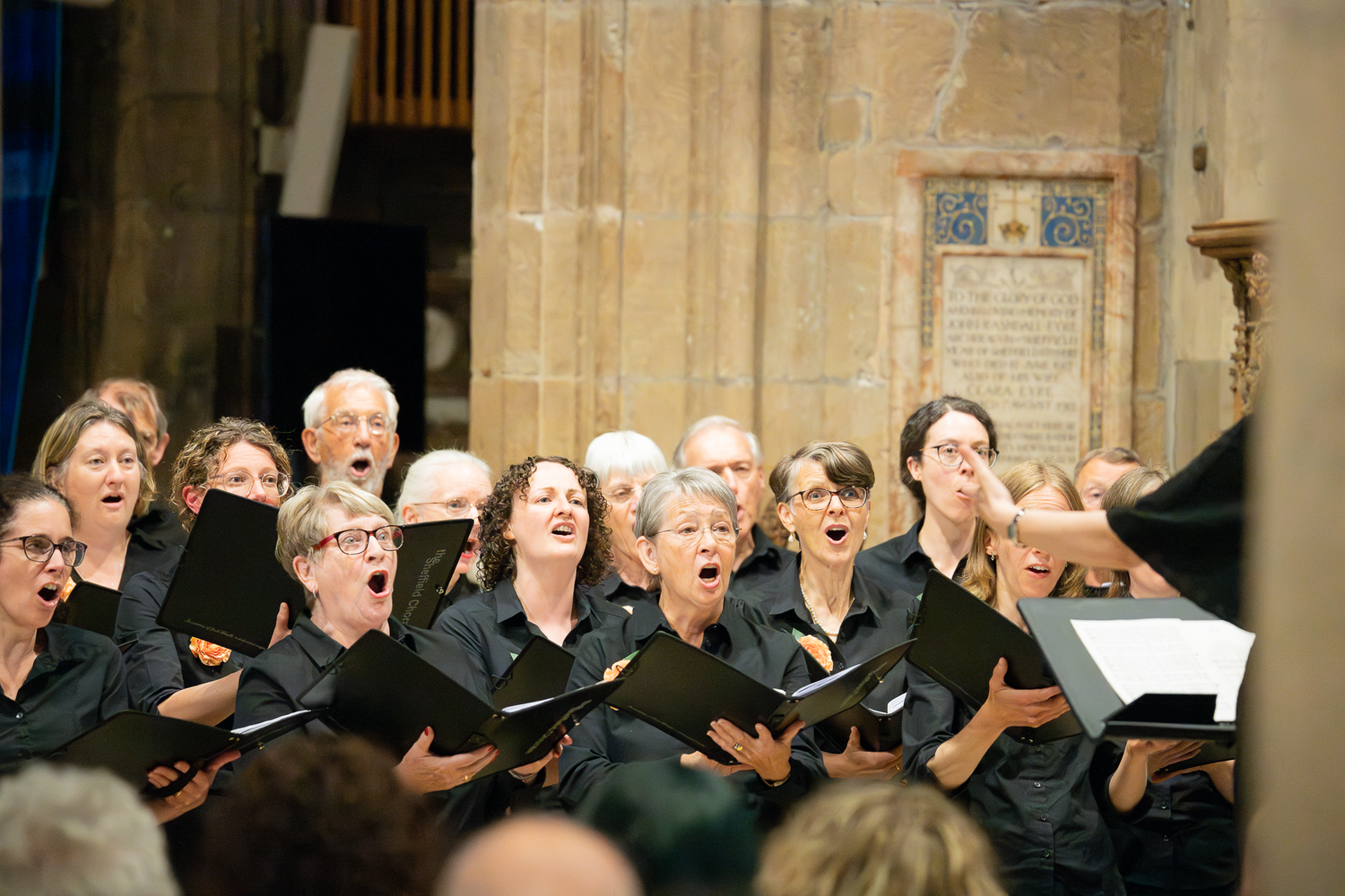 Choir members performing in traditional black attire inside historic stone church.