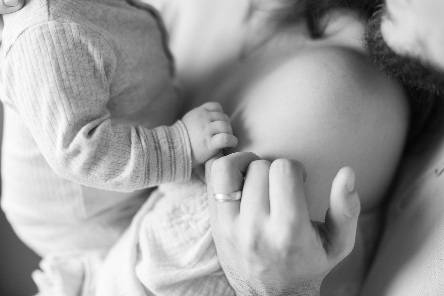Black and white photo series showing tender moments between parent and infant in soft, intimate lighting.
