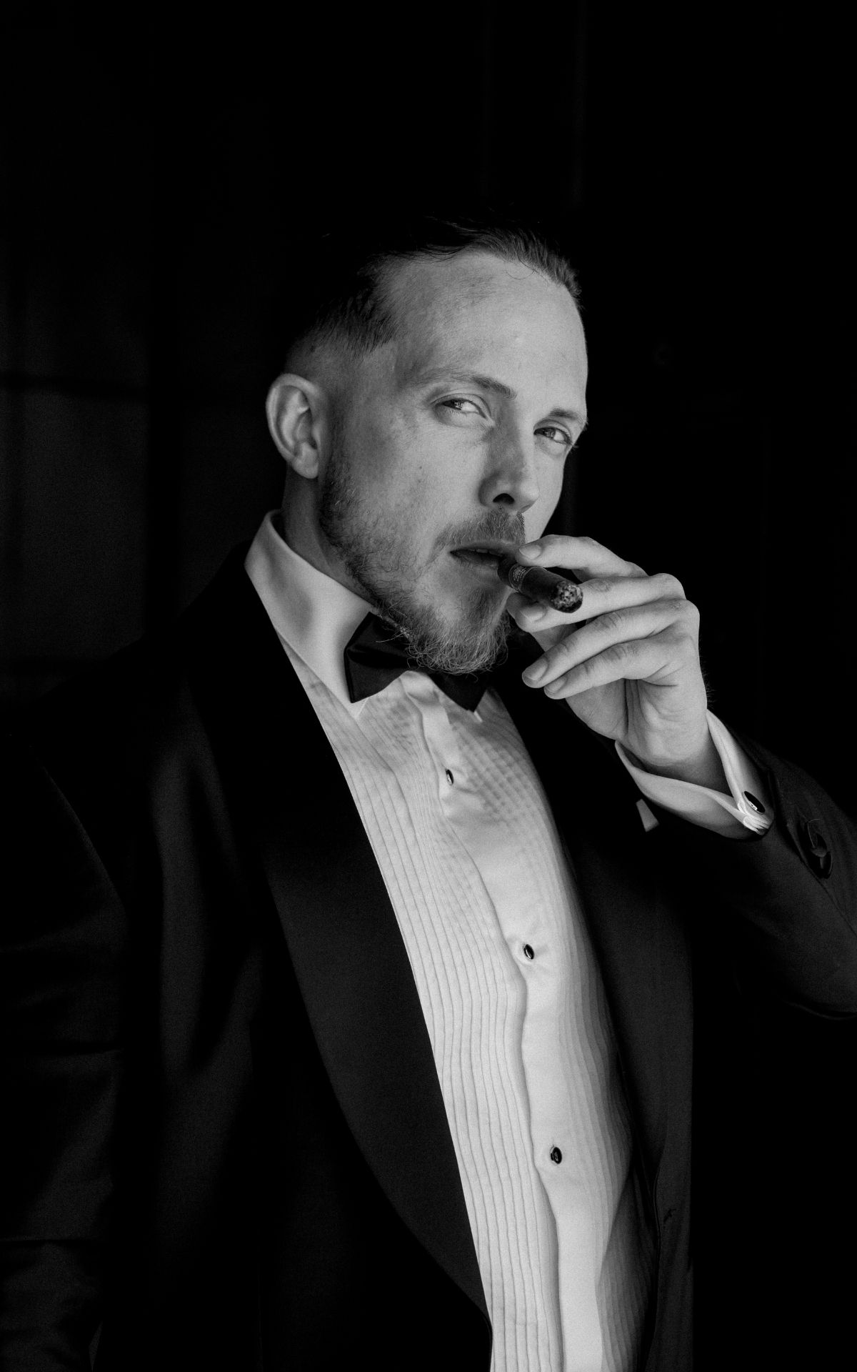 Classic black and white portrait of a groom in a tuxedo smoking a cigar. - JCclick Wedding photo & Film - Best Cape Town Photographer.