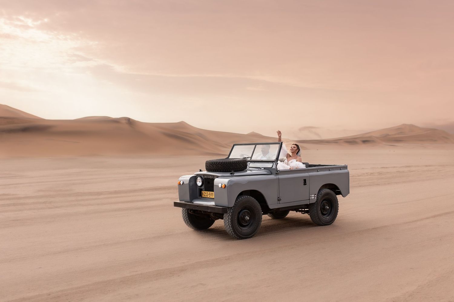 Vintage landrover driving through desert sand dunes at sunset. - JCclick Wedding photo & Film - Best Cape Town Photographer.