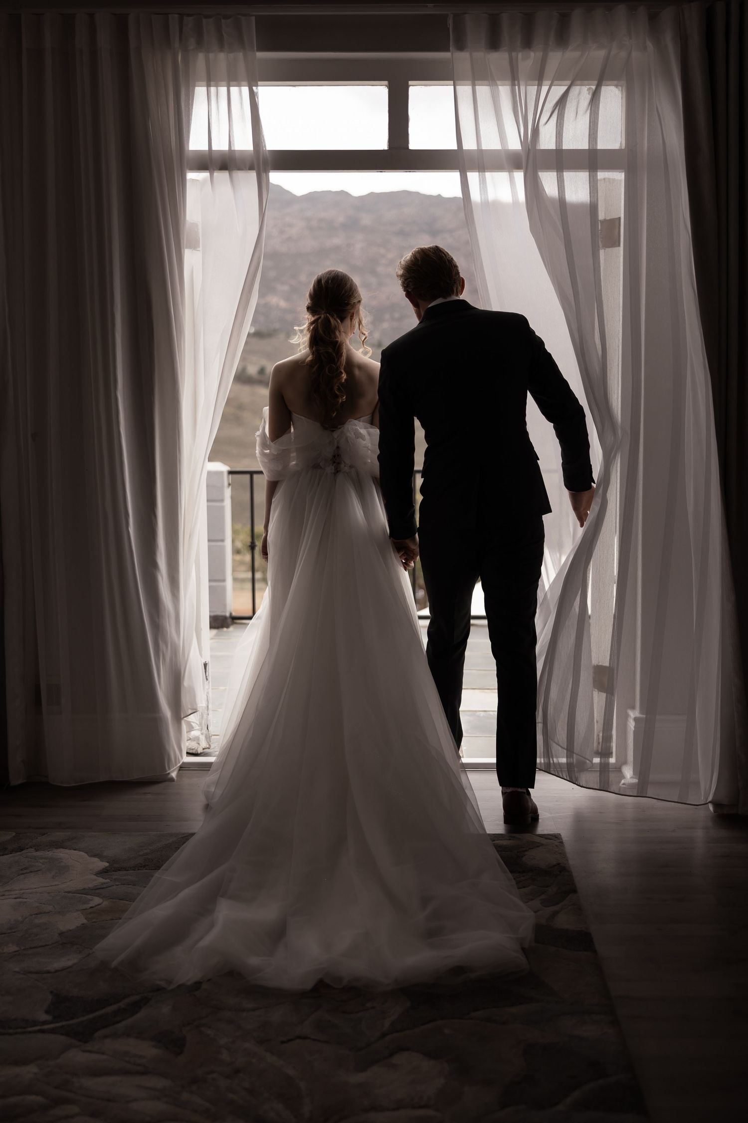 Silhouette of a couple in wedding attire walking through billowing white curtains.  JCclick Wedding photo & Film - Best Cape Town Photograph