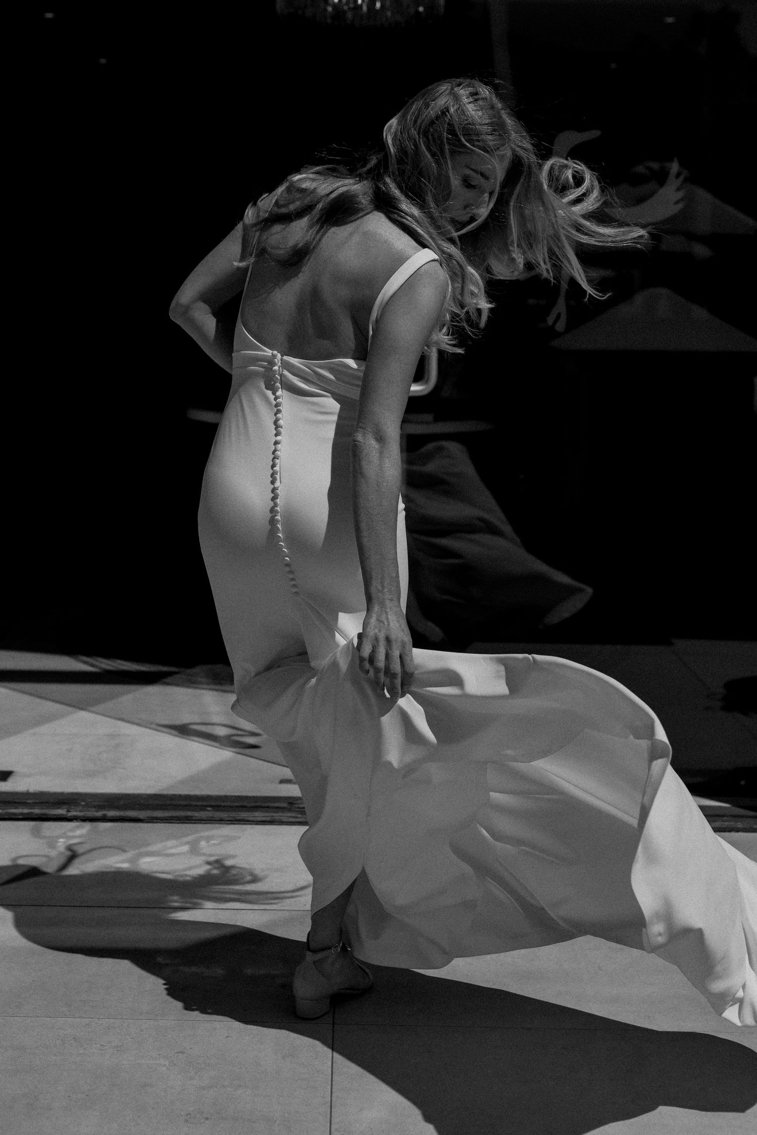 Artistic black and white photo of a flowing white dress against a dark background.