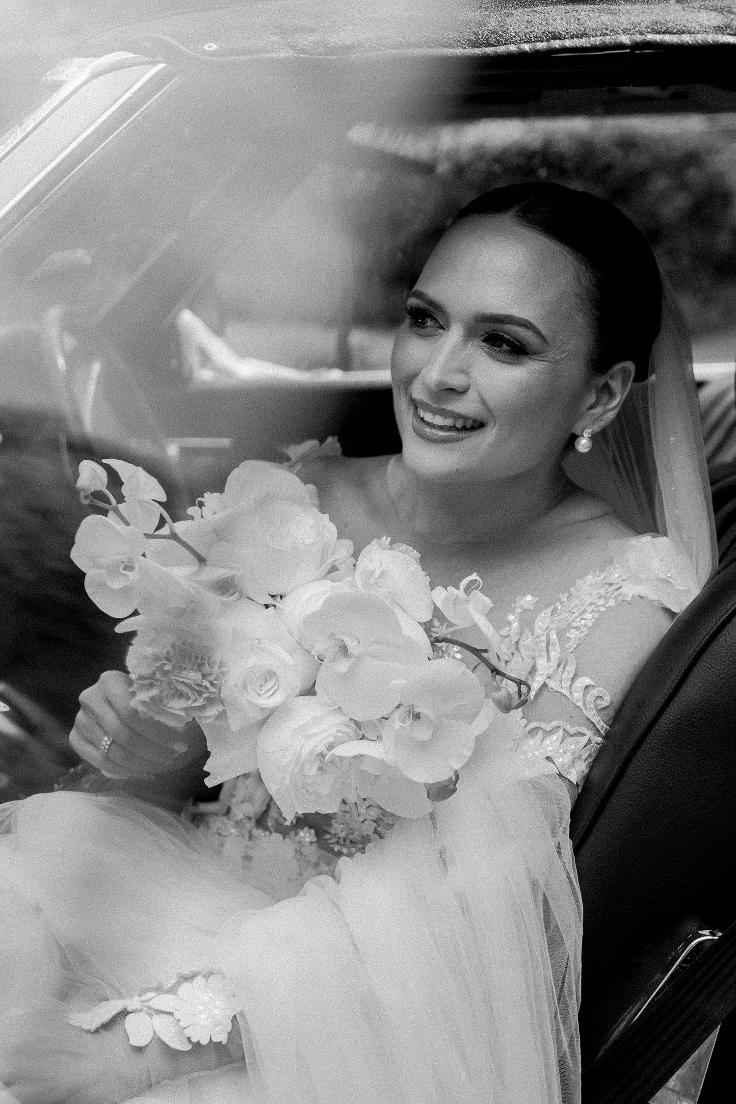 Black and white wedding photo showing a bride in a car with floral details.  JCclick Wedding photo & Film - Best Cape Town Photographer.