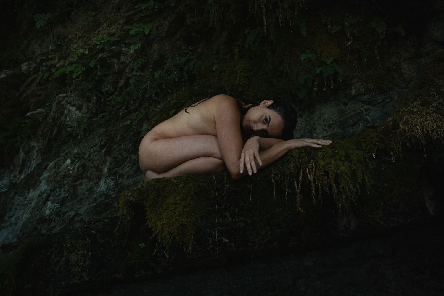 Esperienza di Fotografia Rituale con Camilla Morandin, donna nuda accovacciata su una roccia con il muschio.