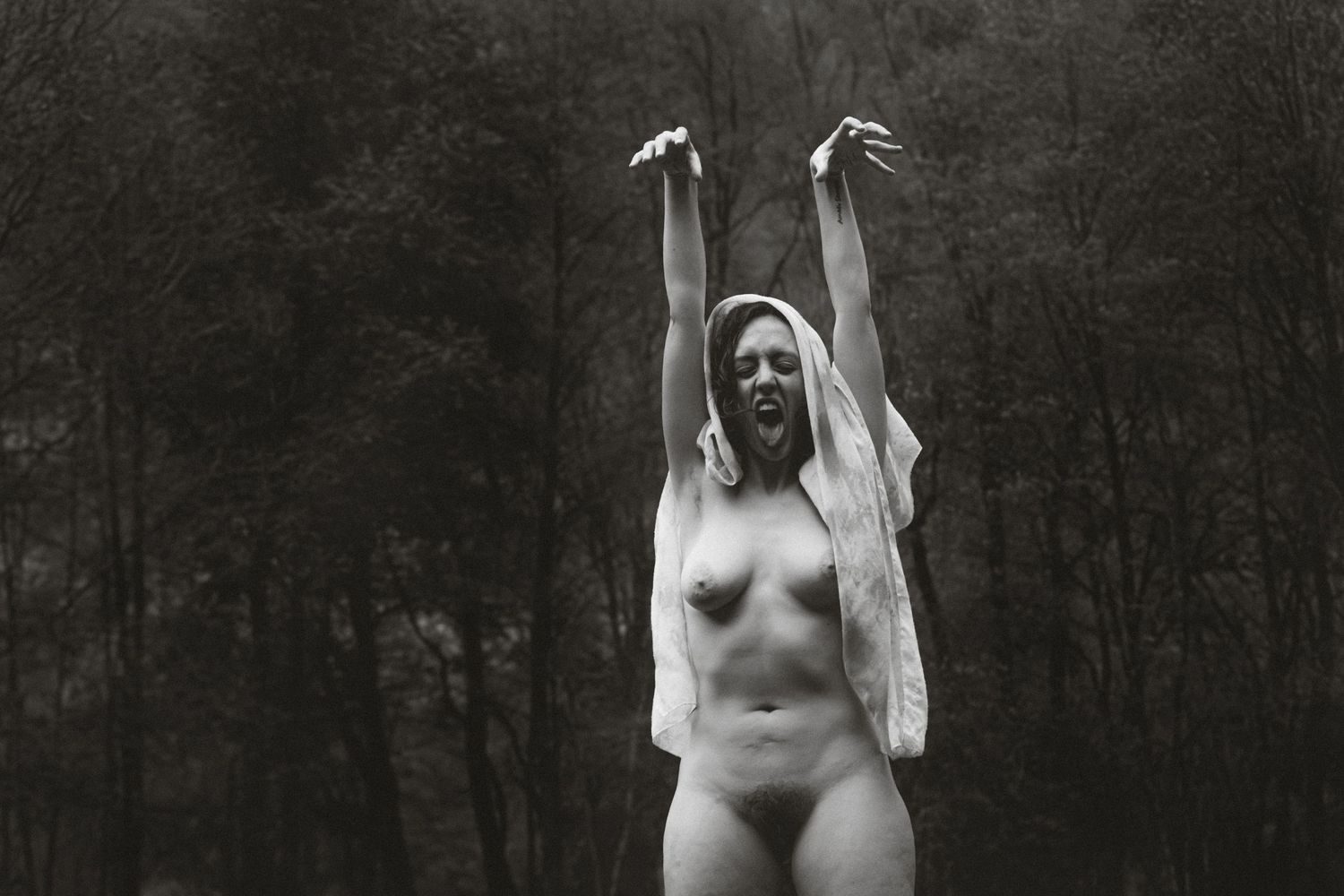 fotografia in bianco e nero di donna nuda mentre fa una linguaccia alla fotocamera. rituale fotografico per liberarsi ed essere autentiche.