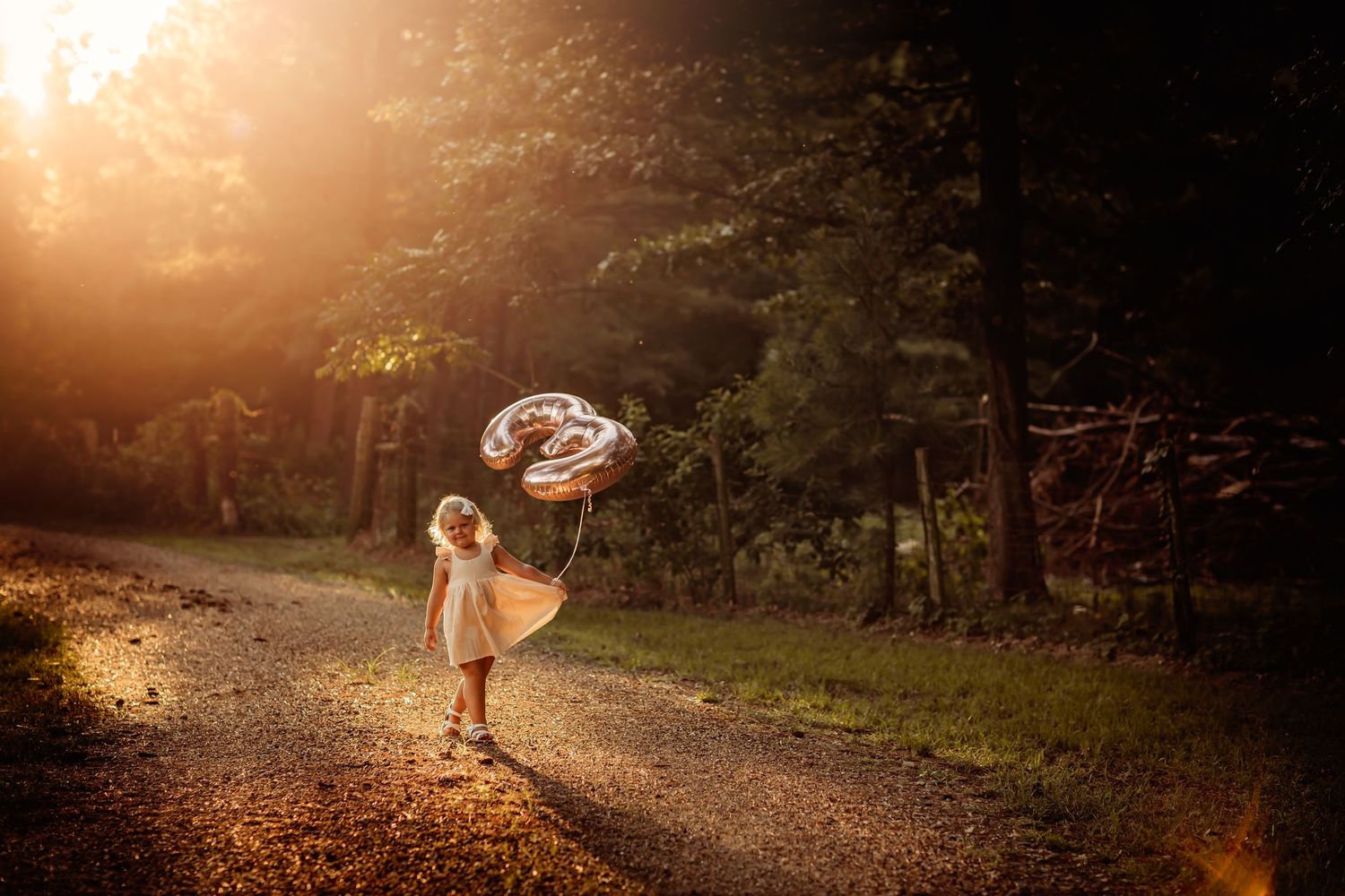 A dreamy sunset scene on a forest path with a figure holding a parasol in golden evening light.