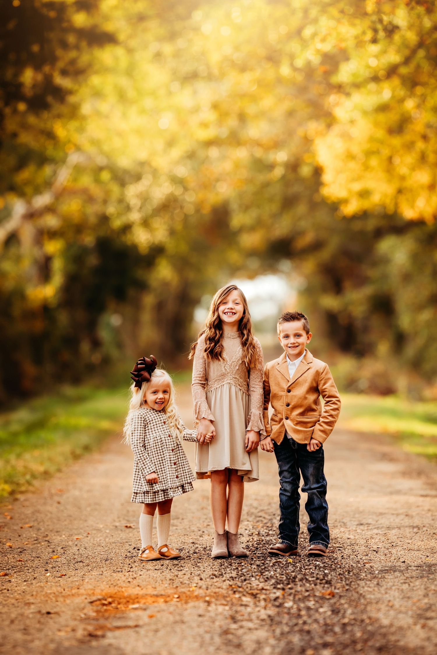 Children walking down a fall path with golden autumn leaves and sunlight.